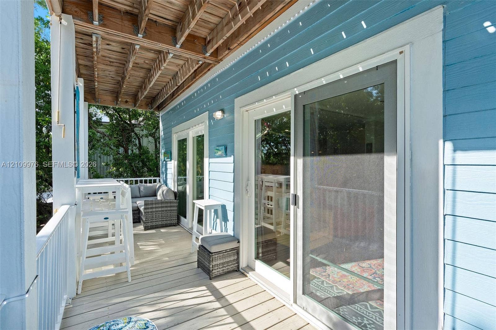 43 Waterways Drive, Key Largo, FL 33037 Covered outdoor deck featuring light-toned wood decking, horizontal lap siding, and sliding glass doors