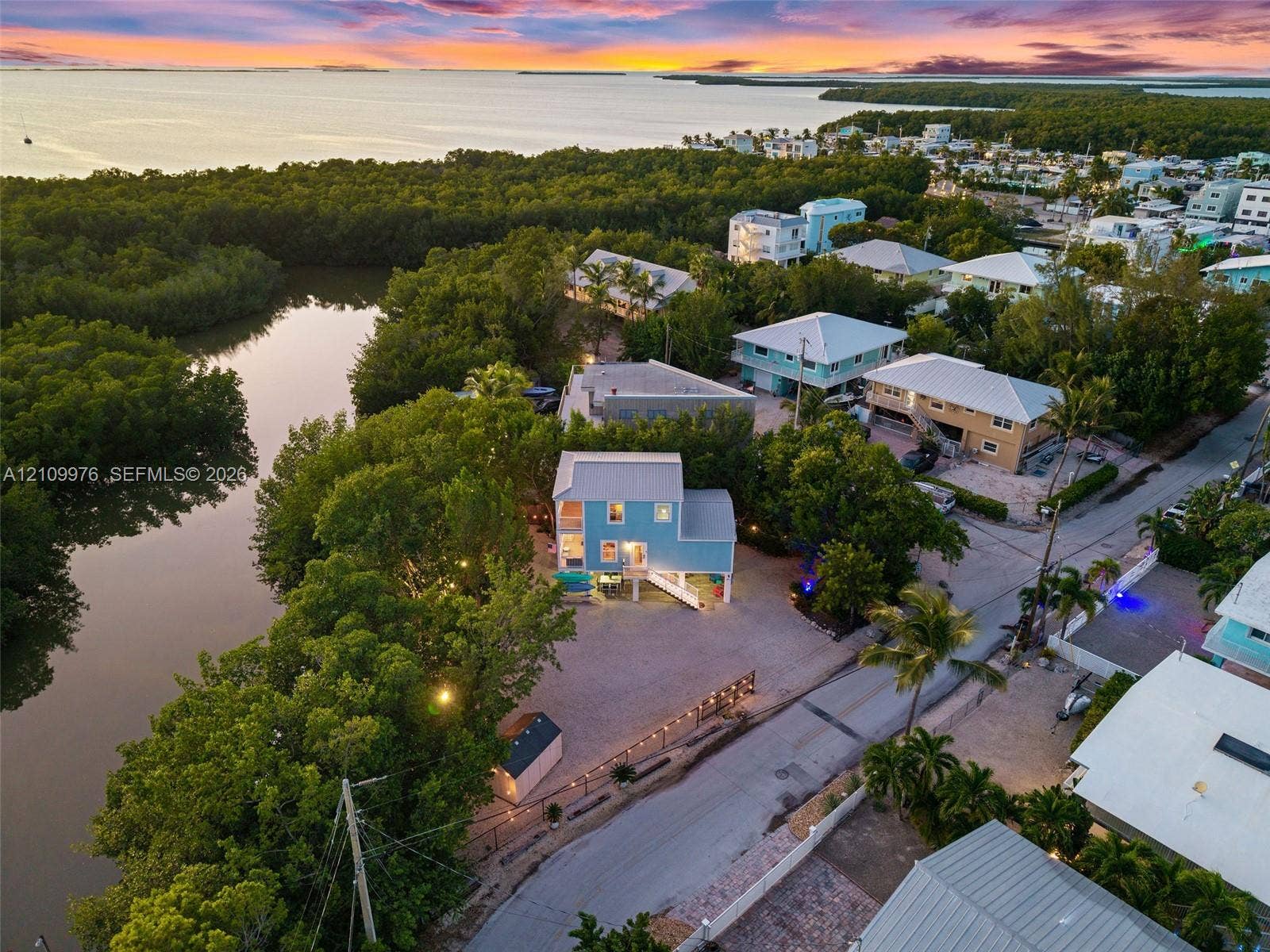 43 Waterways Drive, Key Largo, FL 33037 Aerial perspective of a multi-story residence featuring a metal roof, elevated structural design, expansive gravel grounds, and direct positioning along a natural waterway