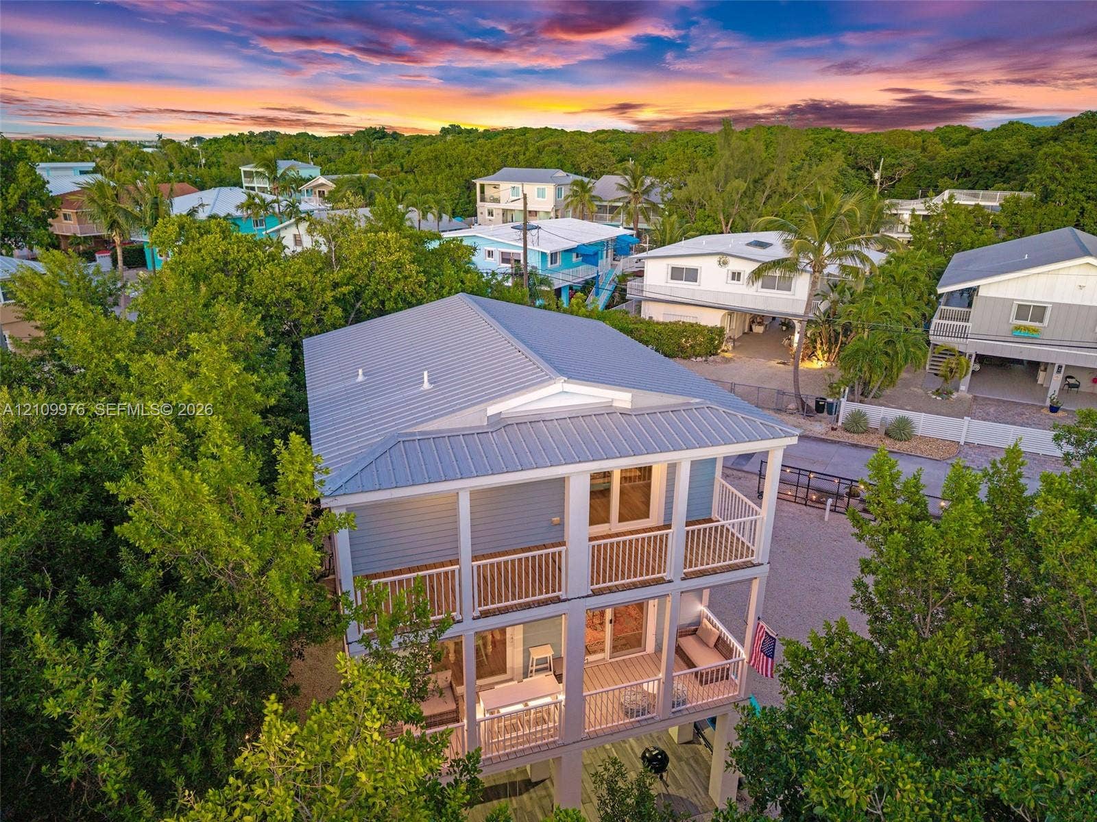 43 Waterways Drive, Key Largo, FL 33037 Multi-level exterior featuring a metal roof, stacked balconies with railings, and elevated pilings