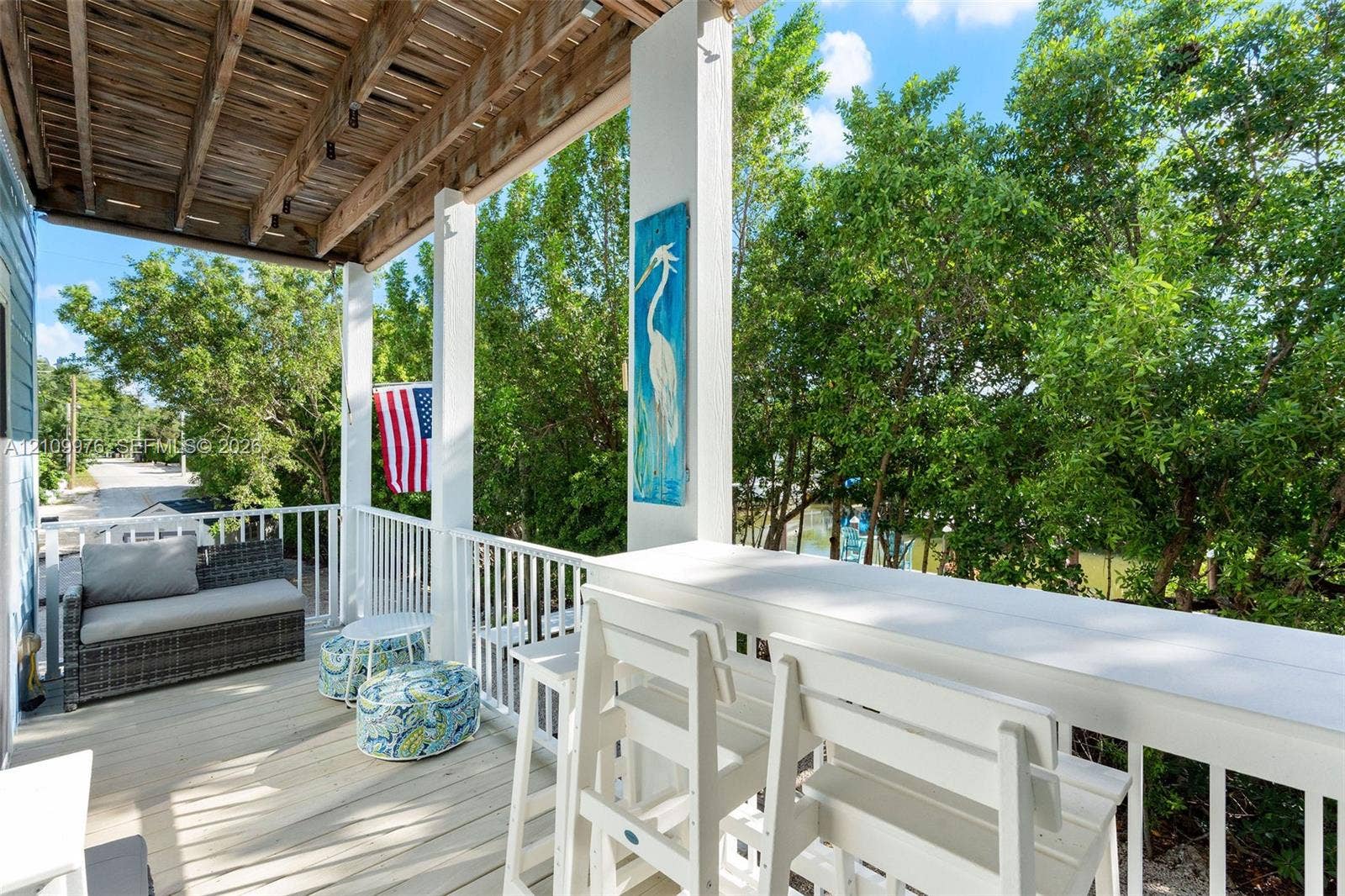 43 Waterways Drive, Key Largo, FL 33037 Covered porch featuring wood-finish decking, white baluster railings, and a built-in elevated counter
