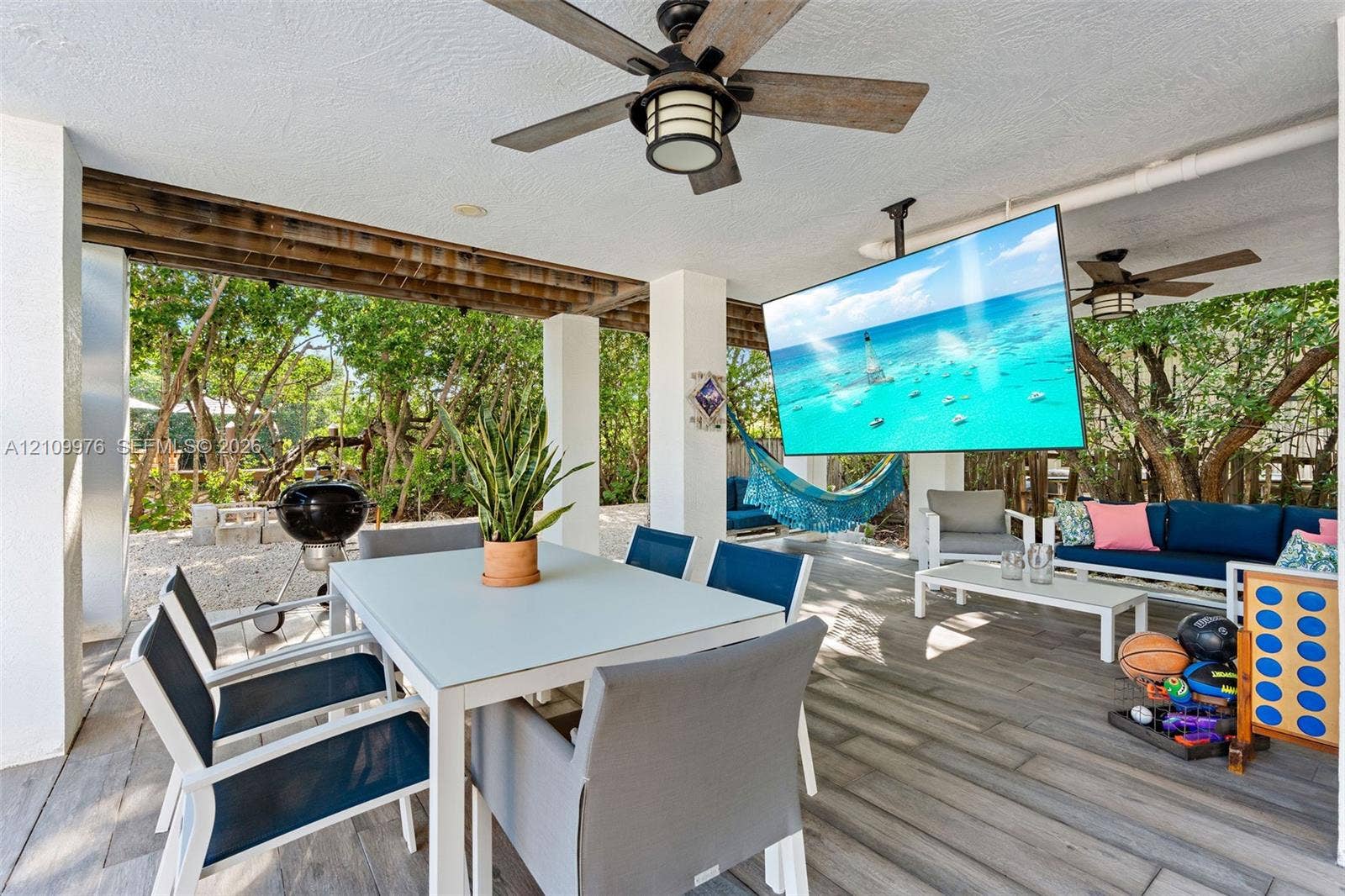 43 Waterways Drive, Key Largo, FL 33037 Covered outdoor living area featuring wood-finish tile flooring, ceiling fans with integrated lighting, and white structural columns