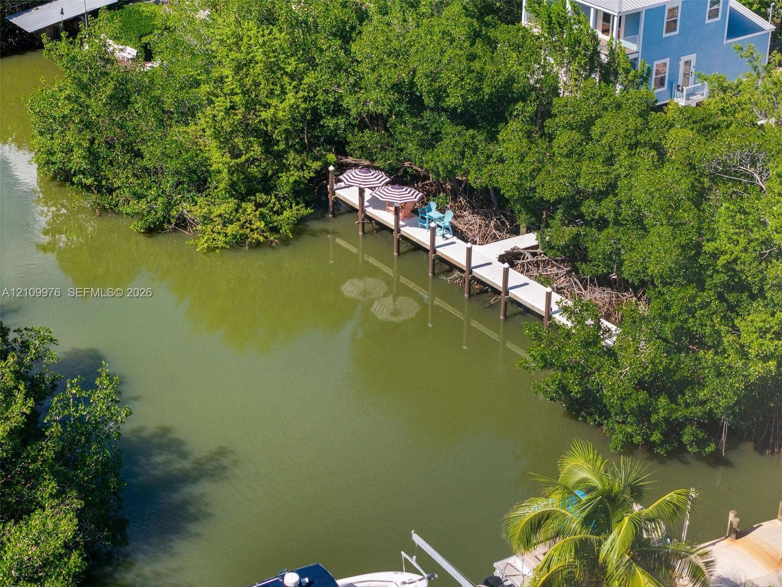 43 Waterways Drive, Key Largo, FL 33037 Private dock featuring a concrete platform, anchored pilings, and dense surrounding foliage