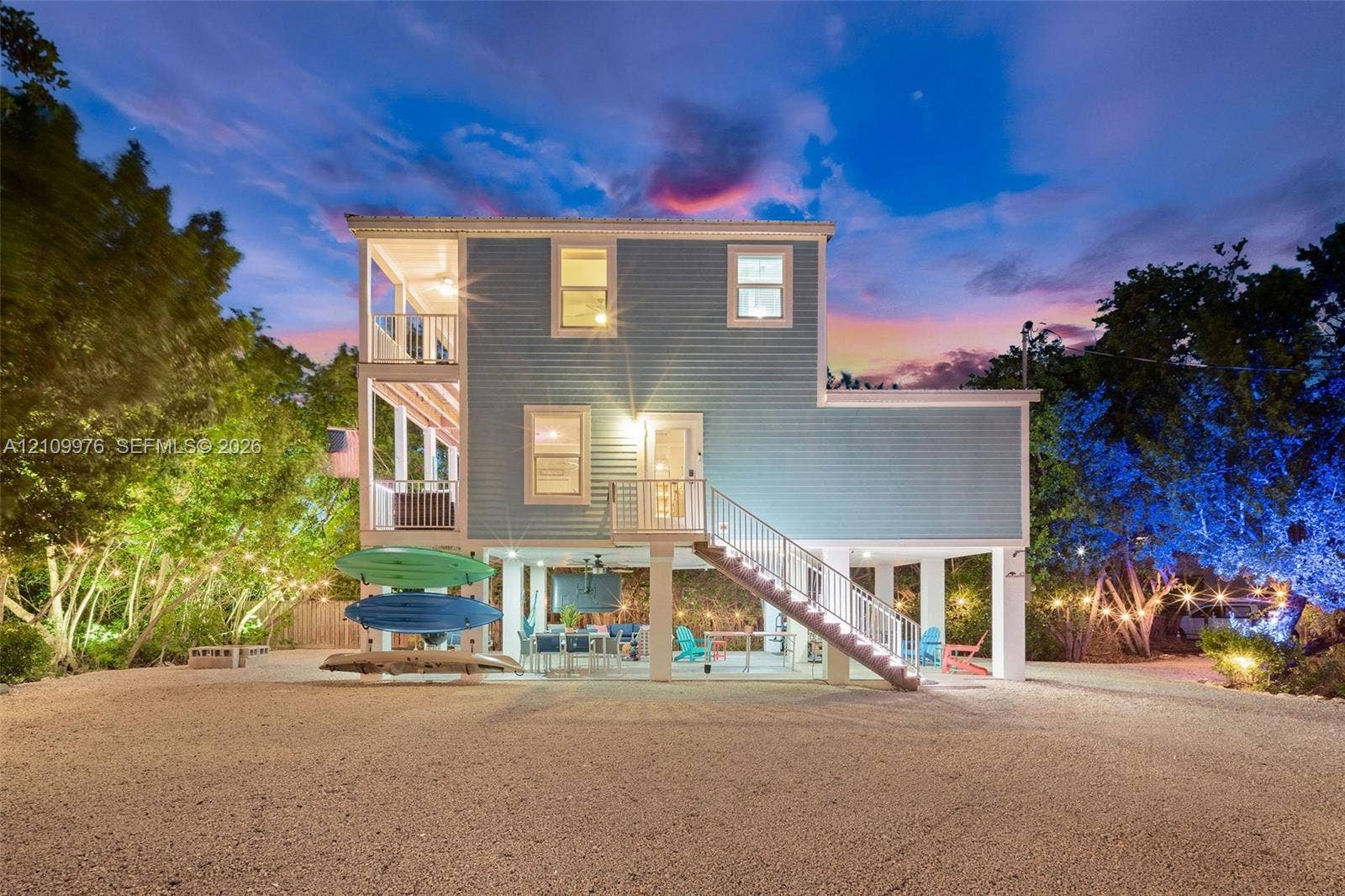 43 Waterways Drive, Key Largo, FL 33037 Multi-level exterior featuring light blue siding, dual stacked covered balconies, and an elevated ground-level concrete patio with metal railings