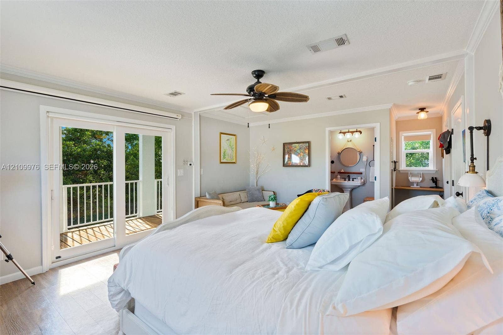 43 Waterways Drive, Key Largo, FL 33037 Room featuring wood-finish flooring, a ceiling fan with integrated lighting, glass sliding doors opening to an exterior balcony, crown molding, and an attached washroom with a pedestal sink and vanity mirror