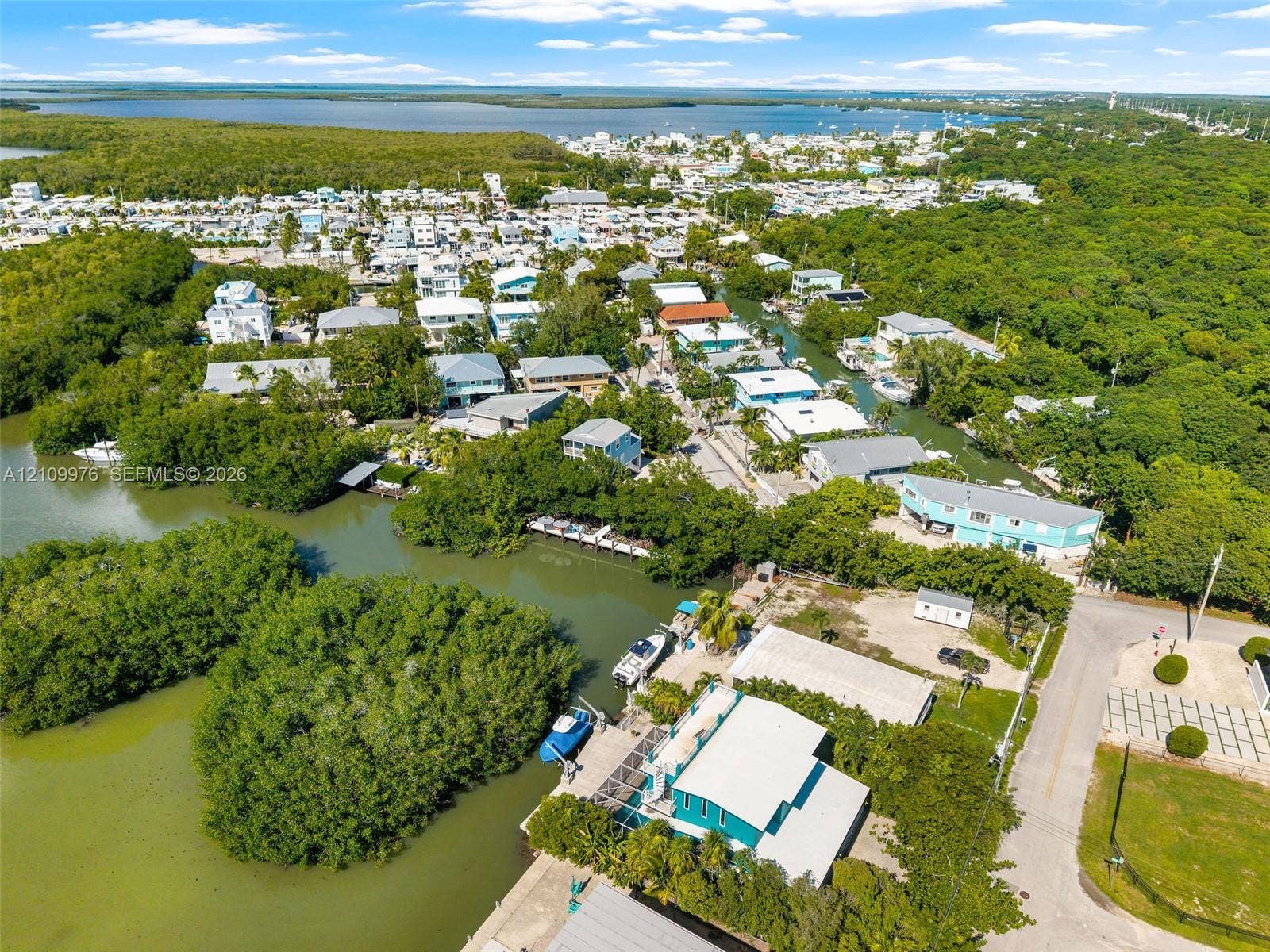 43 Waterways Drive, Key Largo, FL 33037 Aerial perspective of a waterfront property featuring direct canal access, private dockage, surrounding mangrove vegetation, and proximity to open bay waters