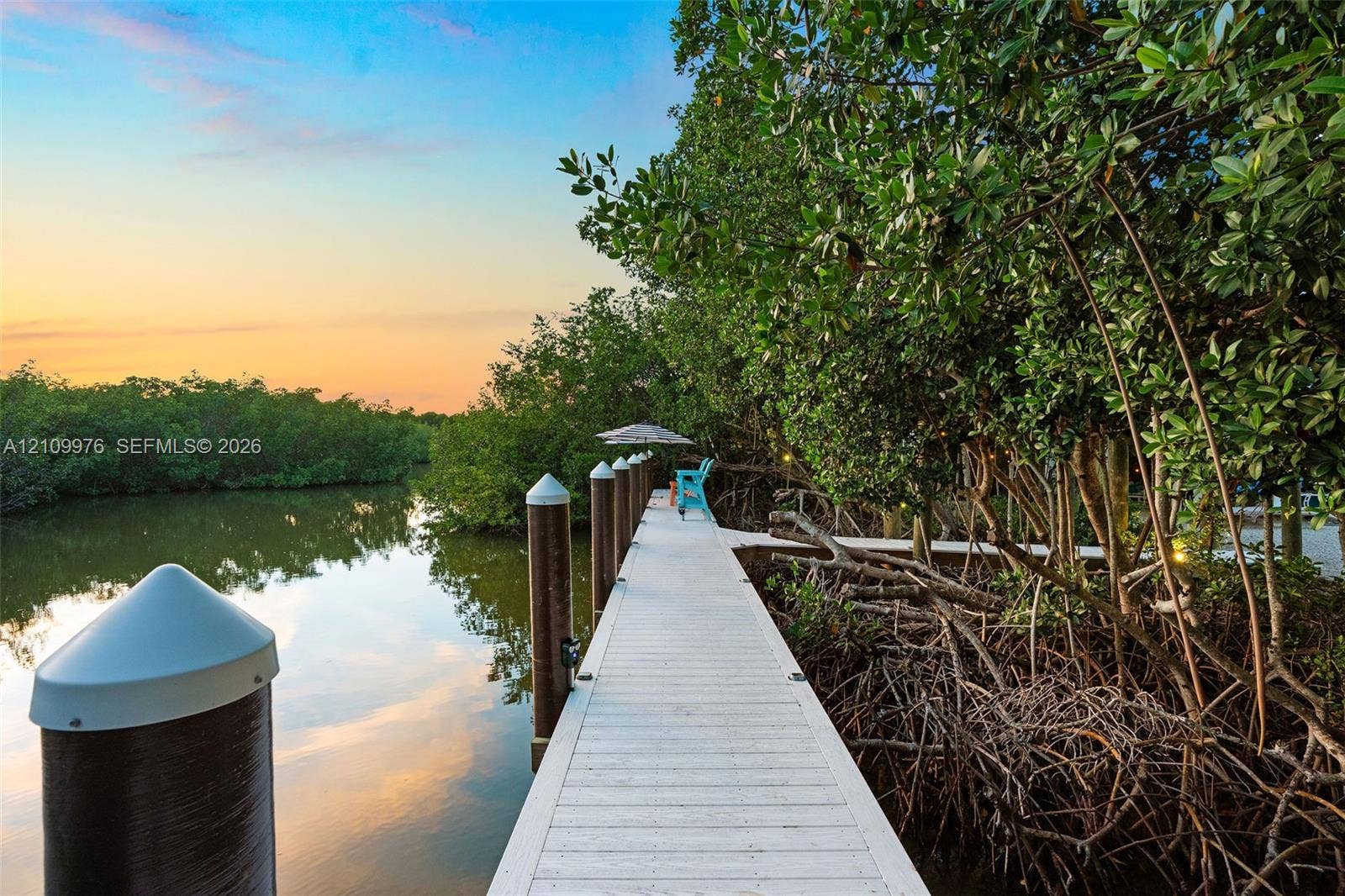 43 Waterways Drive, Key Largo, FL 33037 Private dock featuring composite decking, vertical pilings with conical caps, and mature mangrove surroundings along the water's edge