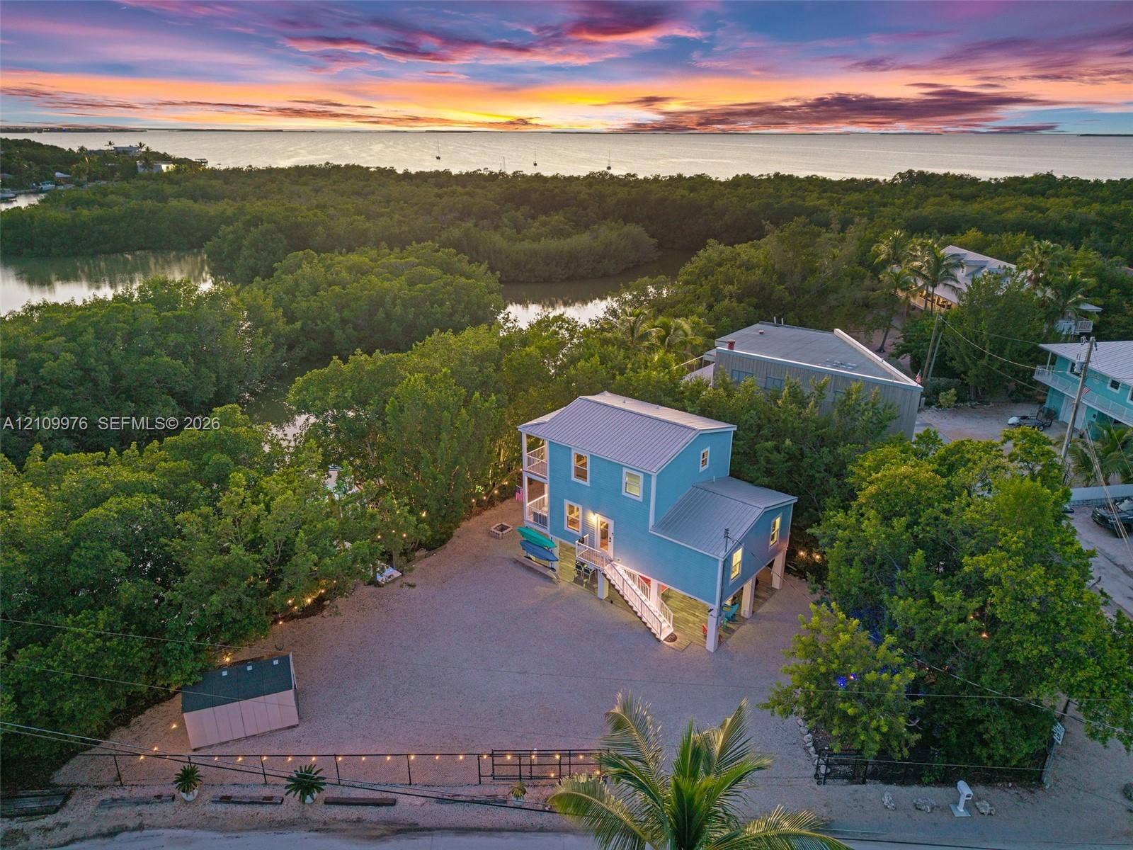 43 Waterways Drive, Key Largo, FL 33037 Two-story residence featuring a metal roof, elevated structural foundation, gravel grounds, and perimeter fencing