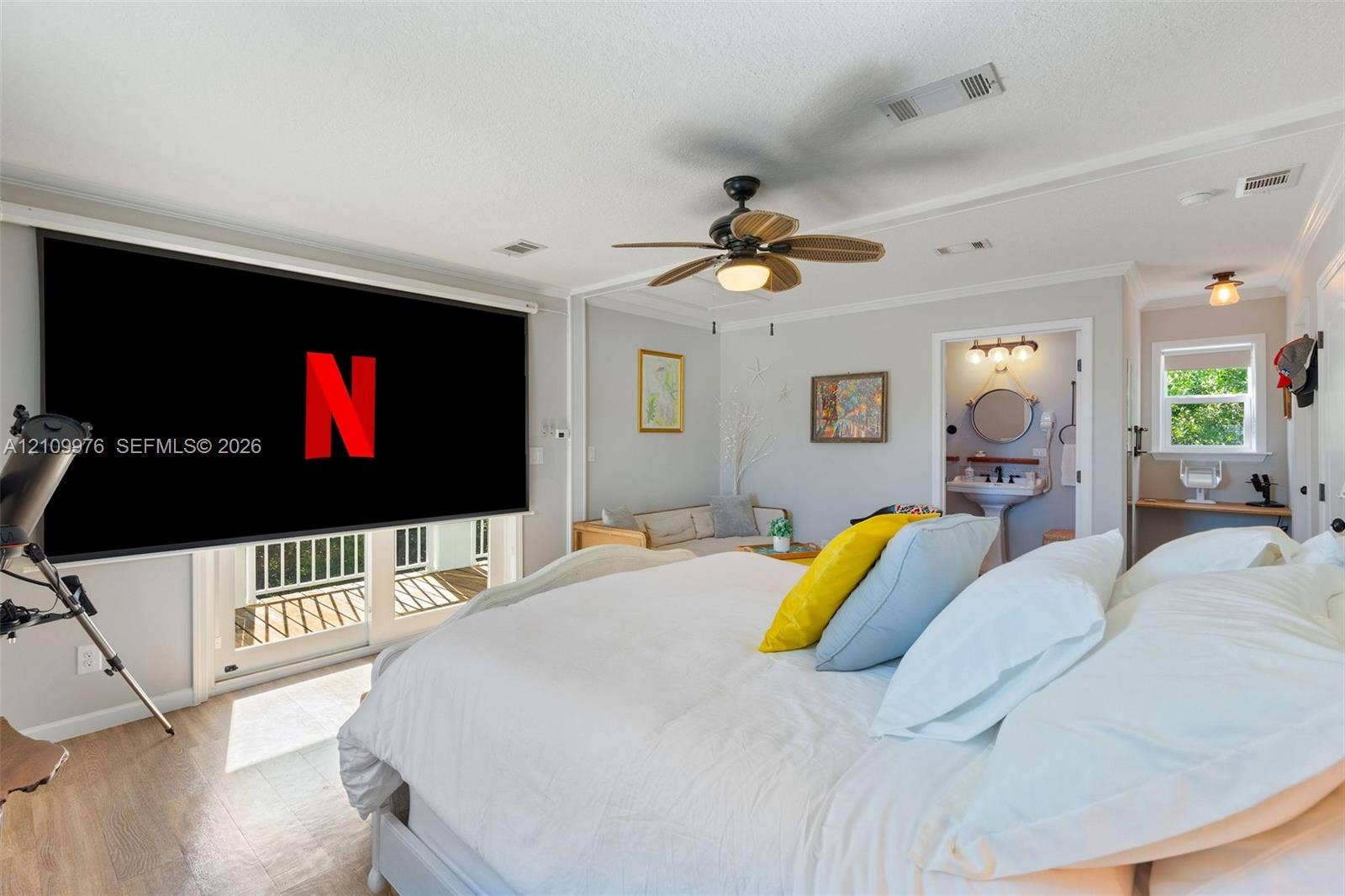 43 Waterways Drive, Key Largo, FL 33037 Room featuring wood-finish flooring, a ceiling fan with integrated lighting, glass sliding doors leading to a balcony, and an attached bathroom with a pedestal sink