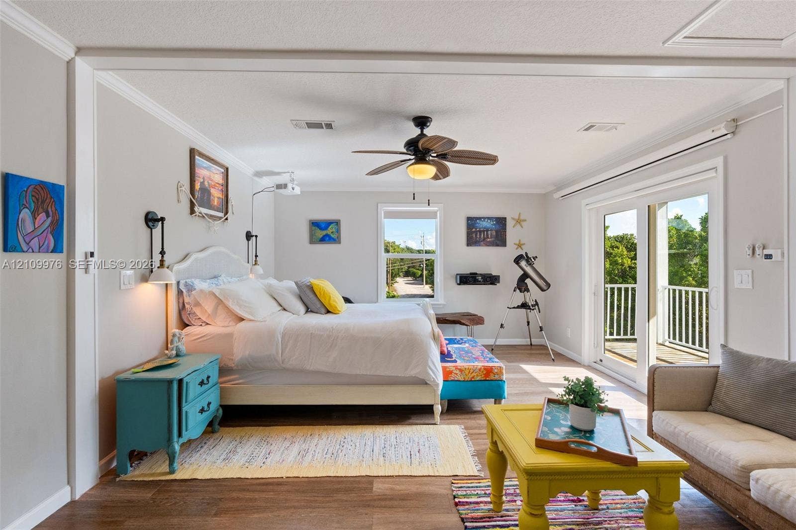 43 Waterways Drive, Key Largo, FL 33037 Living space featuring wood-finish flooring, a ceiling fan with integrated lighting, wall-mounted light fixtures, and glass sliding doors providing access to an exterior balcony