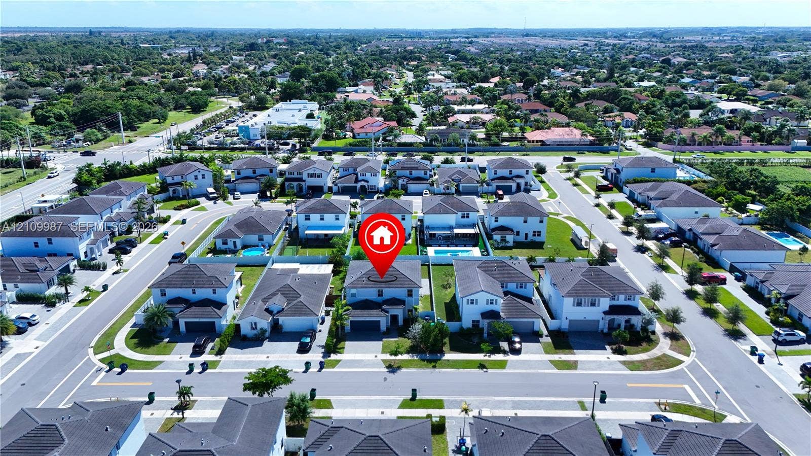 12740 SW 214th Terrace, Miami, FL 33177 Aerial perspective of a two-story residence featuring a shingled roof, stucco exterior, and an attached two-car garage