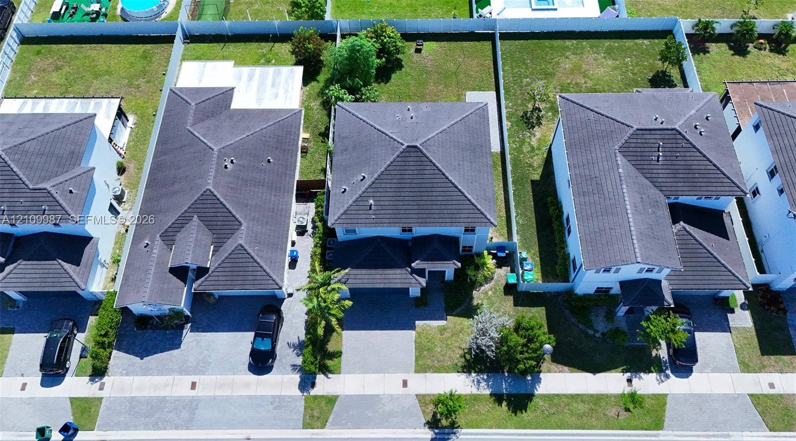 12740 SW 214th Terrace, Miami, FL 33177 Aerial perspective of suburban properties featuring multi-level dwellings, tile roofing, paved driveways, and fenced rear grounds