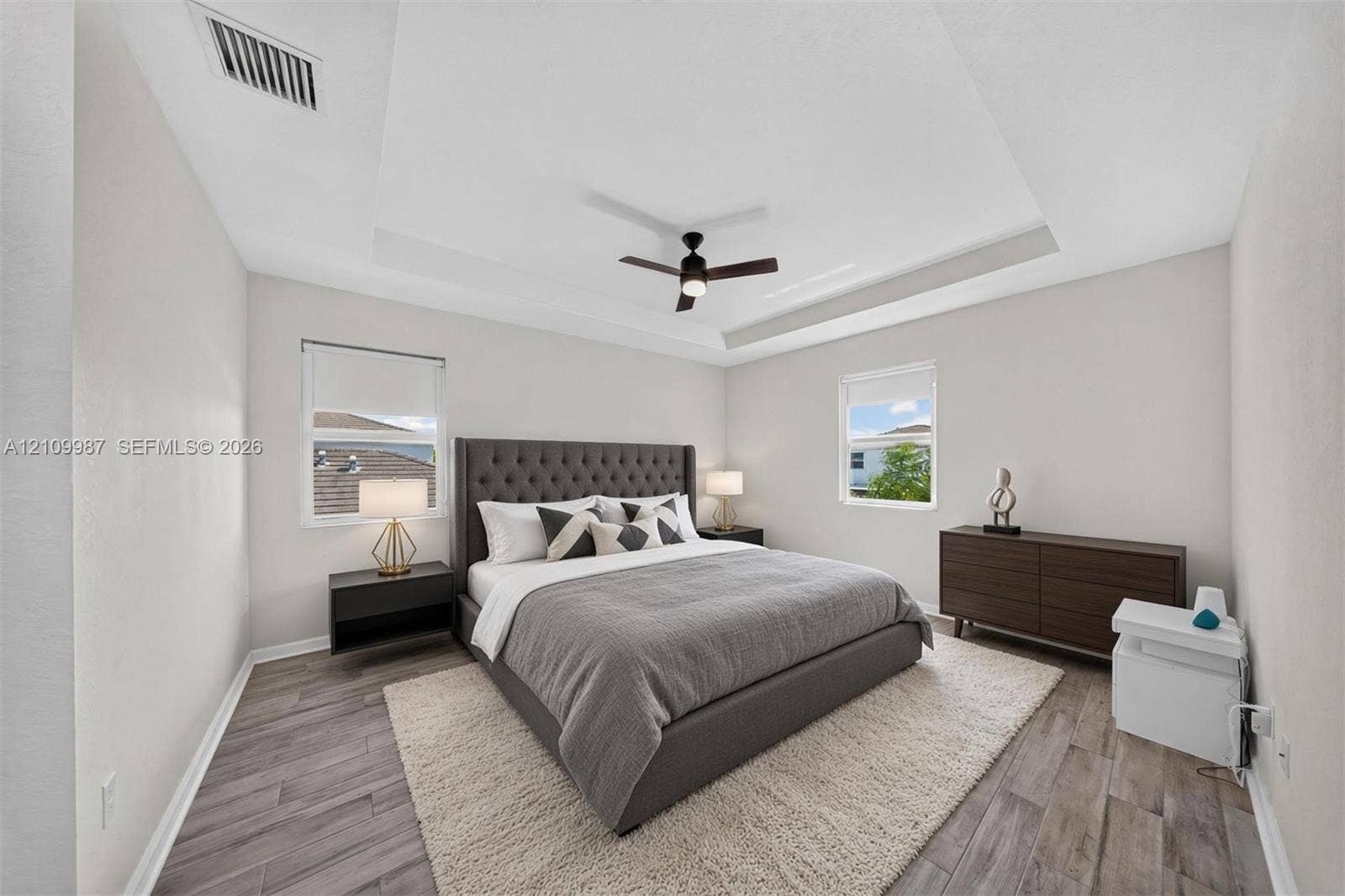 Tray ceiling, porcelain flooring, and a central ceiling fan with integrated lighting