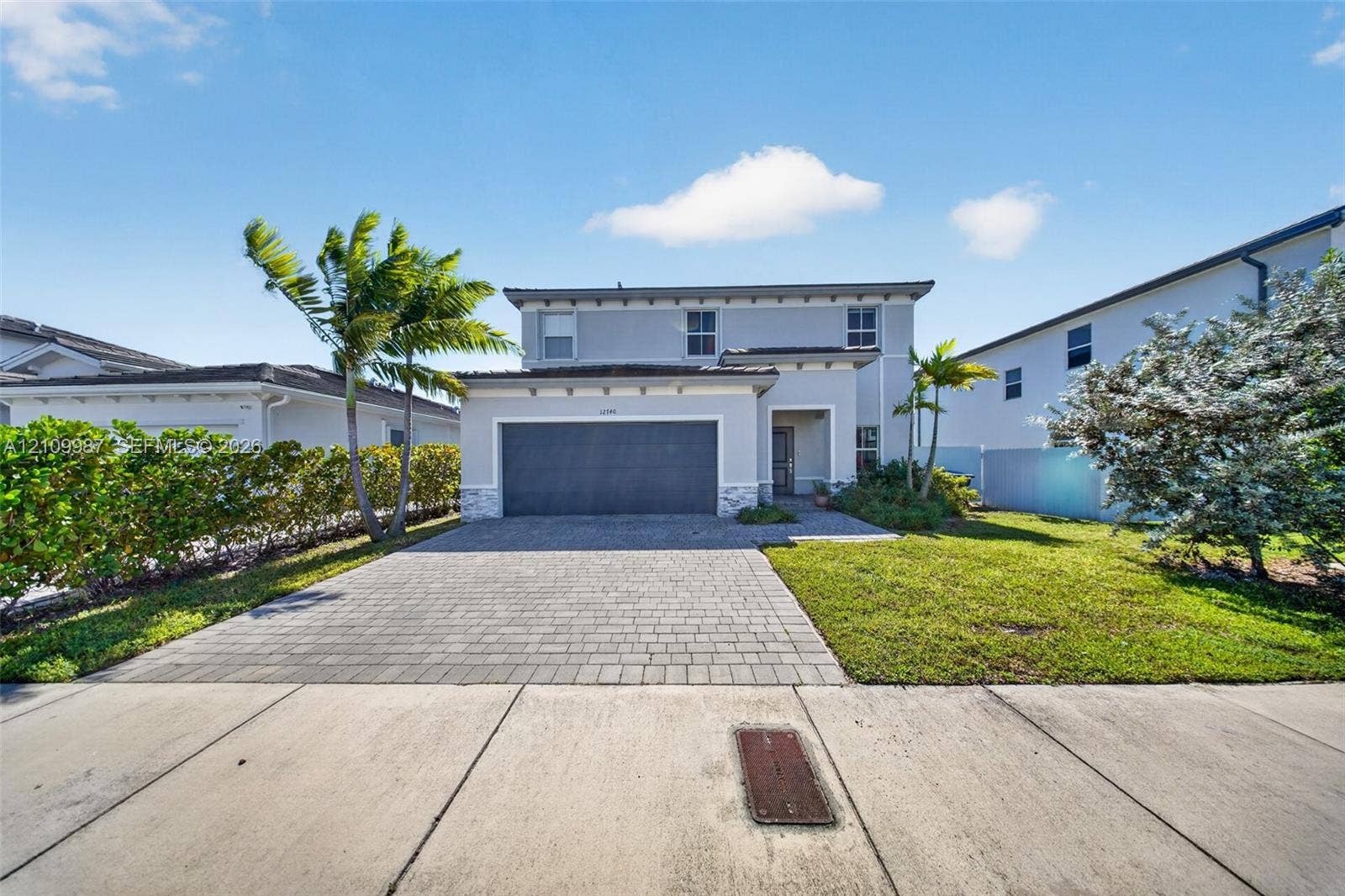 12740 SW 214th Terrace, Miami, FL 33177 Two-story exterior featuring a paver driveway, an attached multi-car garage, and stone veneer accents