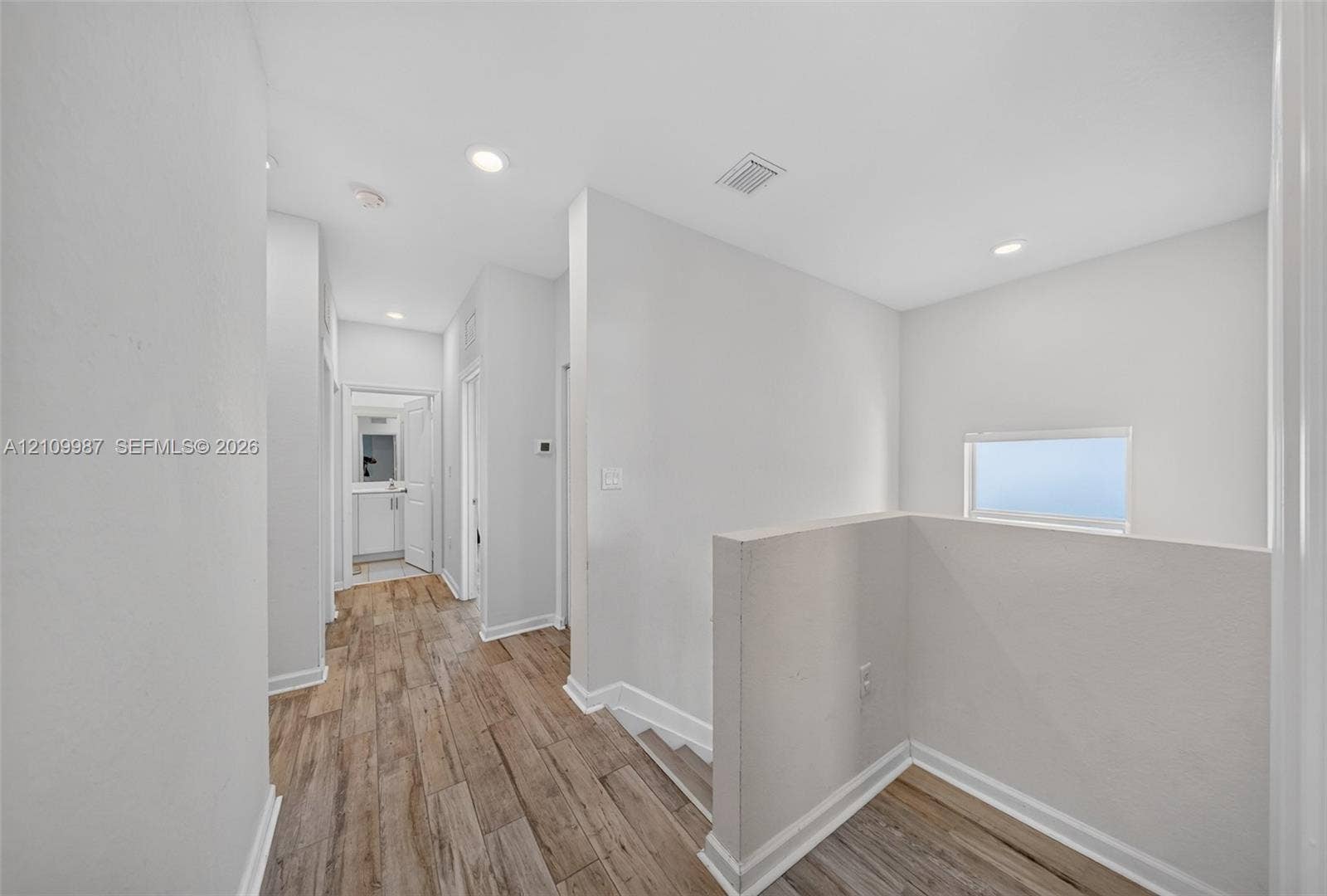 Hallway featuring porcelain flooring, recessed lighting, and a half-wall partition