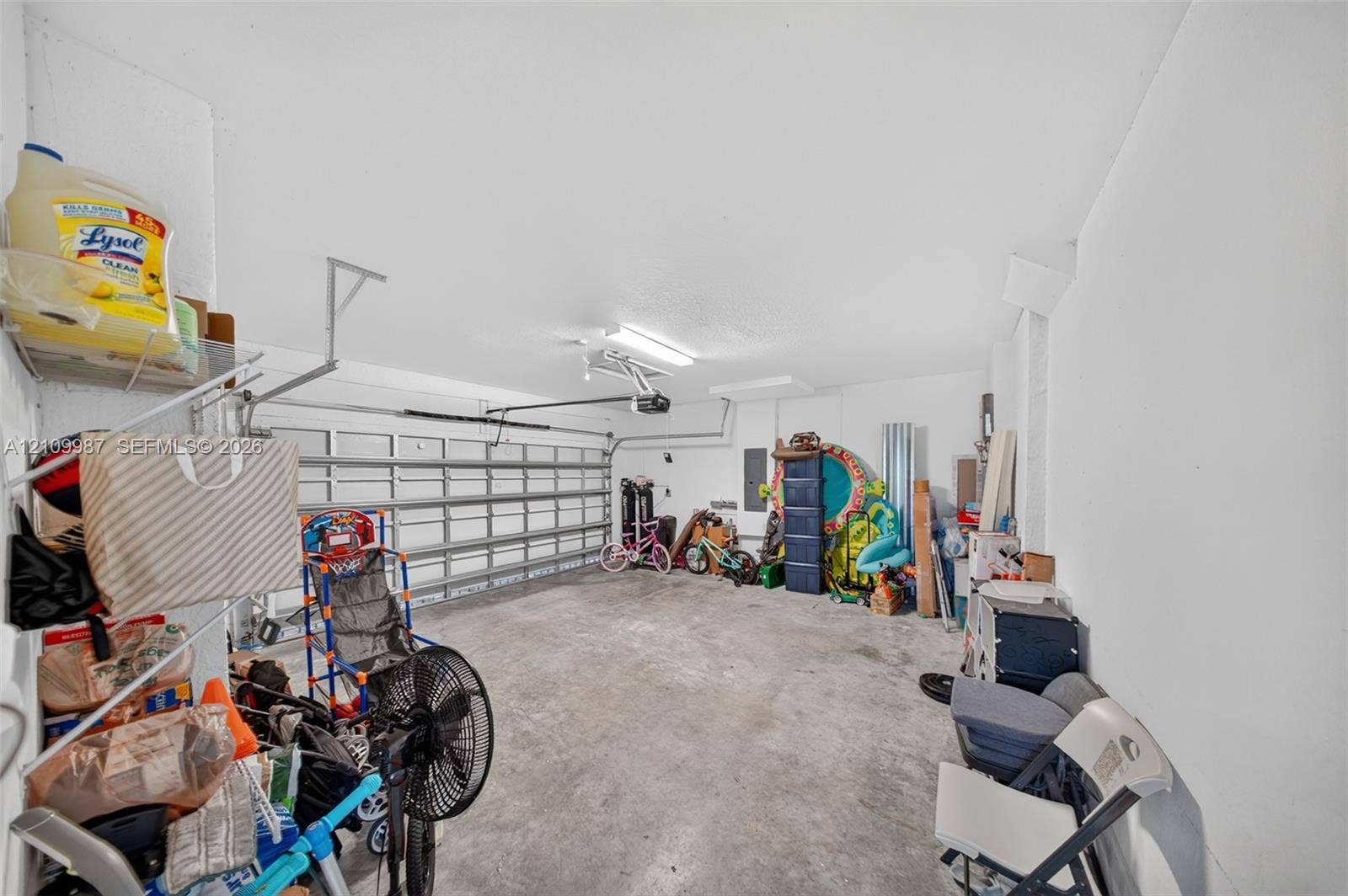 Enclosed garage featuring a metal overhead door, concrete flooring, and ceiling-mounted light fixture