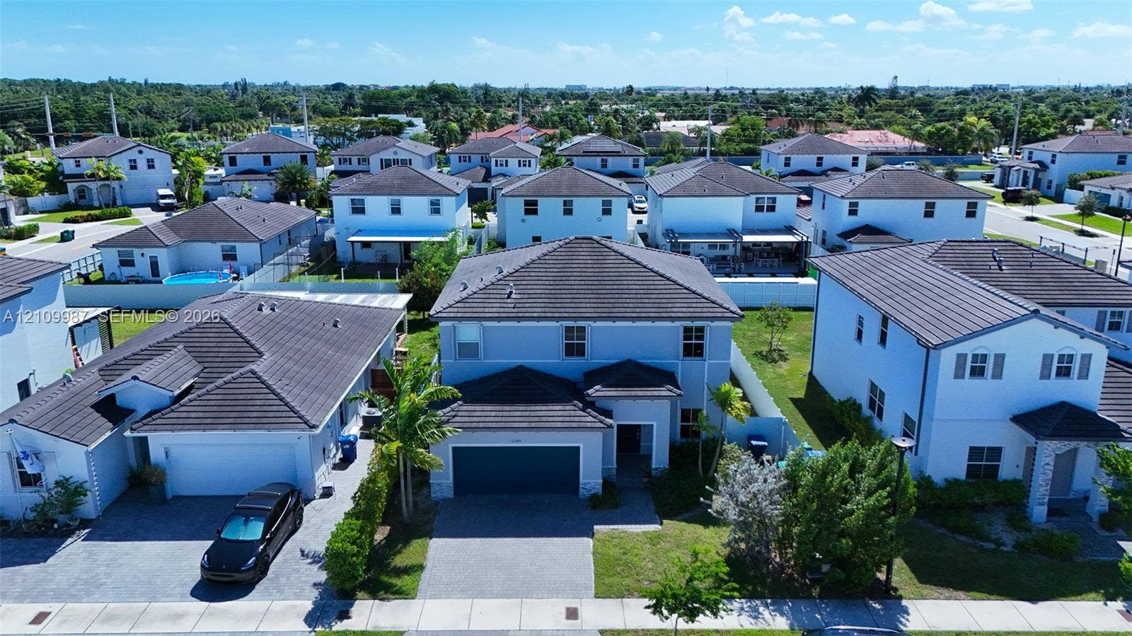 12740 SW 214th Terrace, Miami, FL 33177 Aerial perspective of a two-story residence featuring a dark tile roof, smooth-stucco exterior, paver driveway, and a two-car garage