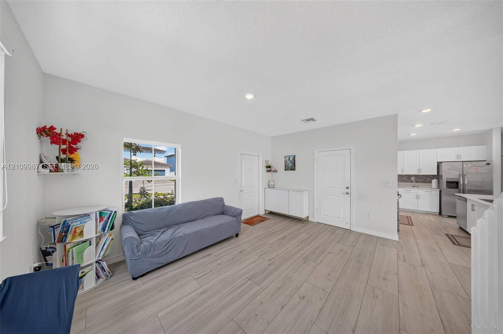 Open floor plan featuring porcelain-finish flooring, recessed lighting, and white cabinetry