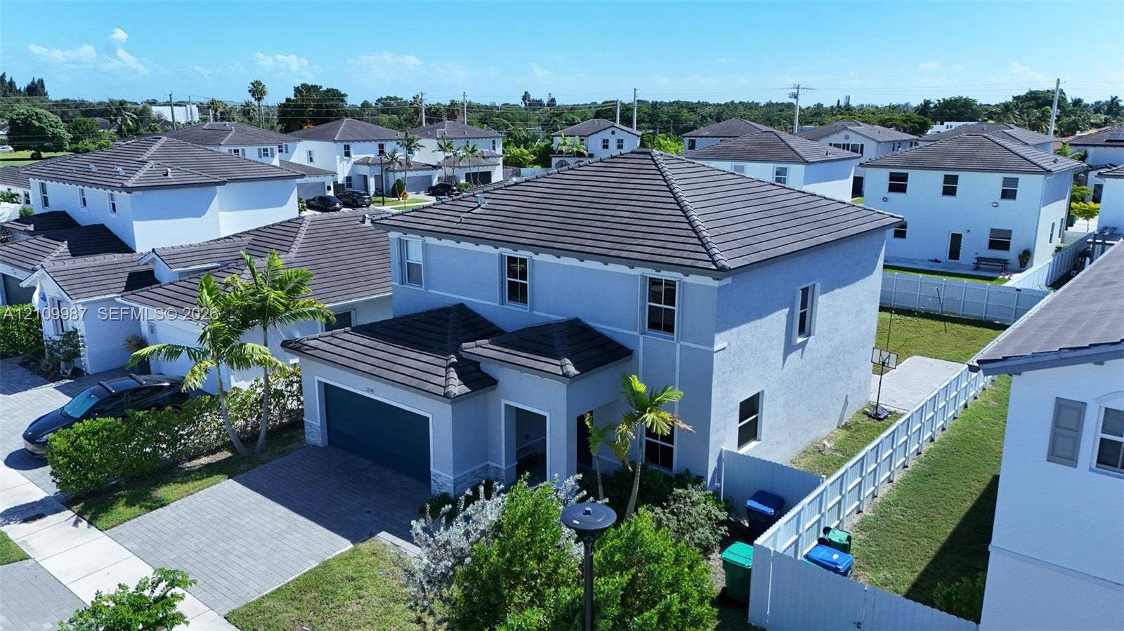 12740 SW 214th Terrace, Miami, FL 33177 Two-story exterior featuring a hip roof with tile shingles, stucco siding, and a paved driveway