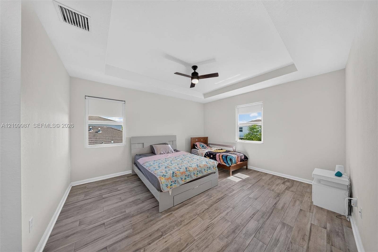 Room interior featuring tray ceiling, porcelain tile flooring, and integrated ceiling fan with light fixture