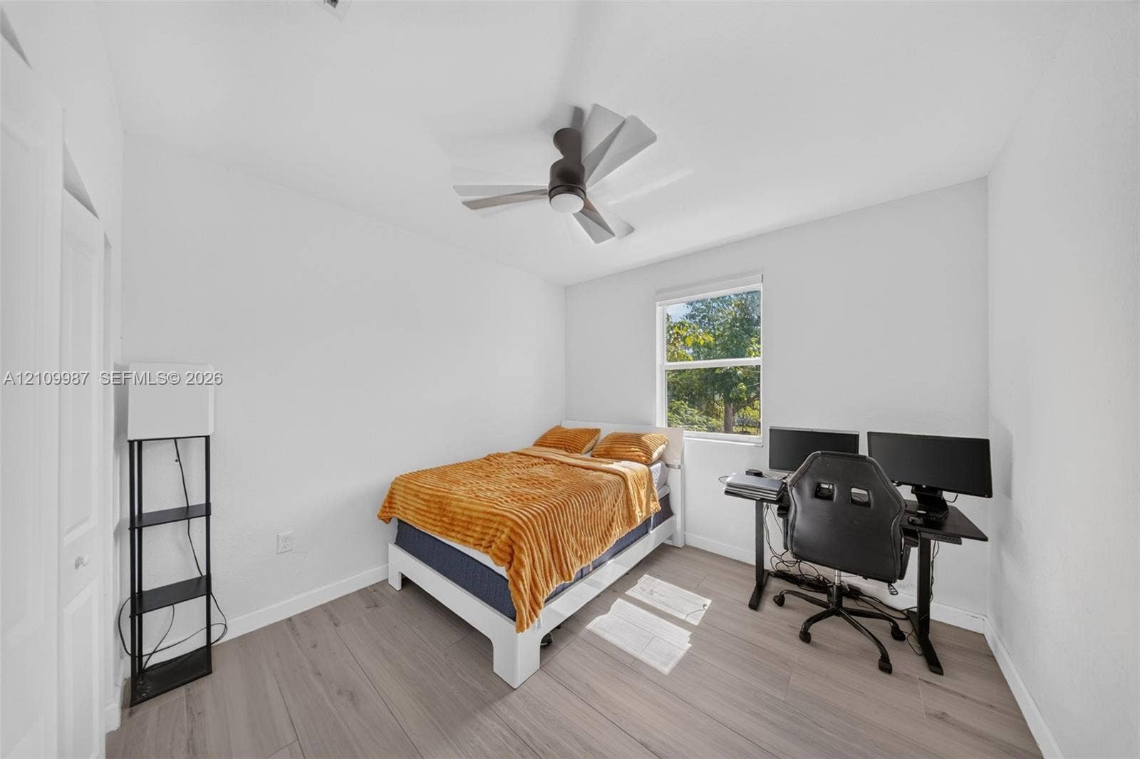 Neutral-toned room featuring porcelain flooring, a contemporary multi-blade ceiling fan, and natural light provided by a single-pane window