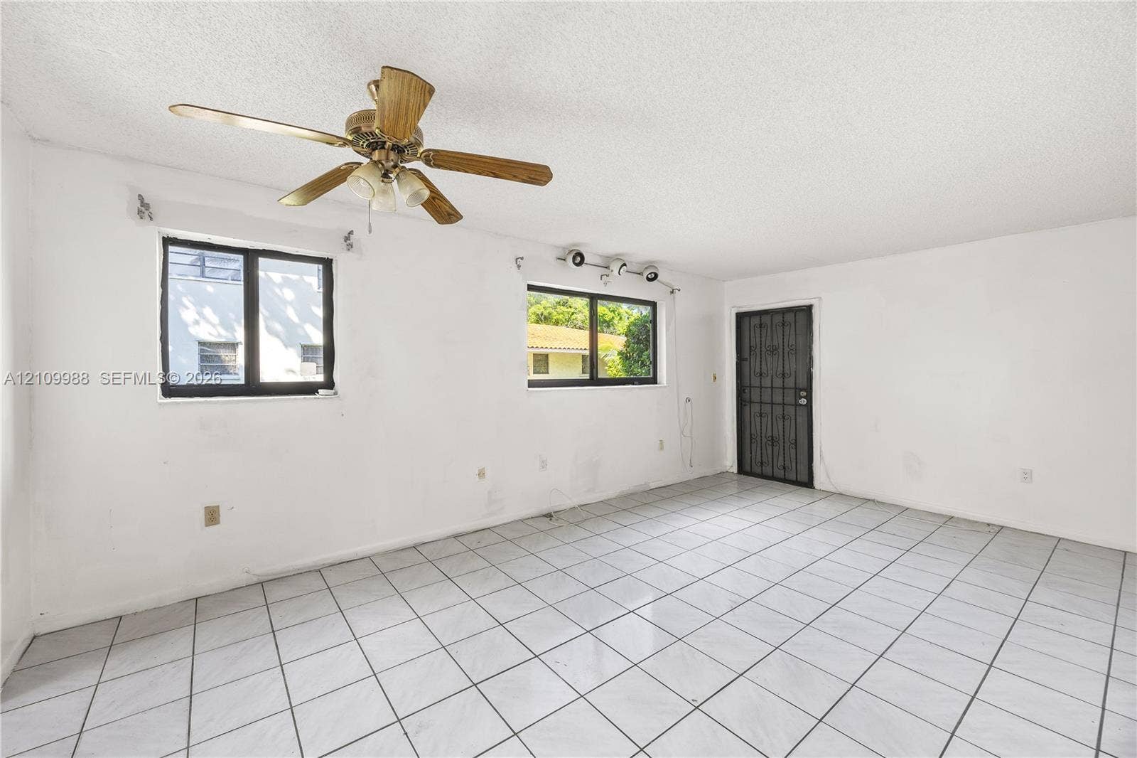 13946 NE 4th Avenue, #13946, Miami, FL 33161 Interior space featuring white tile flooring, ceiling fan with light fixture, multi-pane windows, and a metal security door