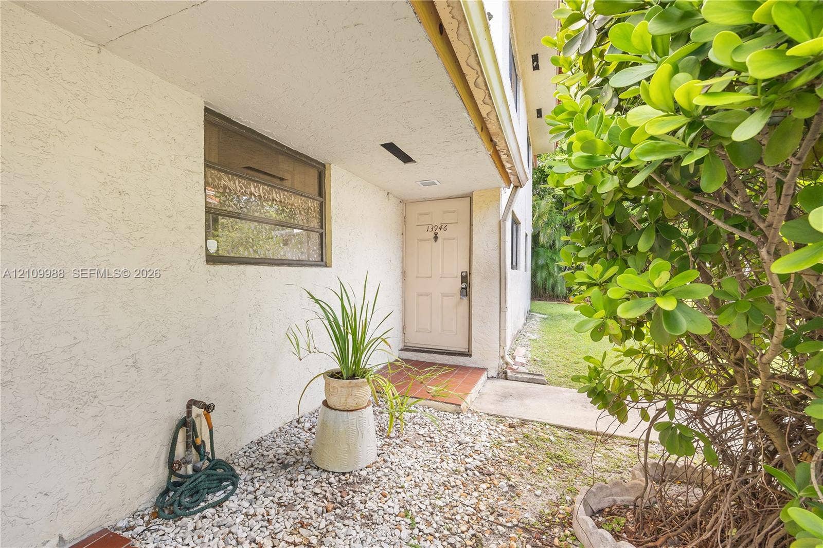 13946 NE 4th Avenue, #13946, Miami, FL 33161 Stucco exterior featuring a recessed entry, multi-pane window, tiled landing, and decorative gravel hardscaping