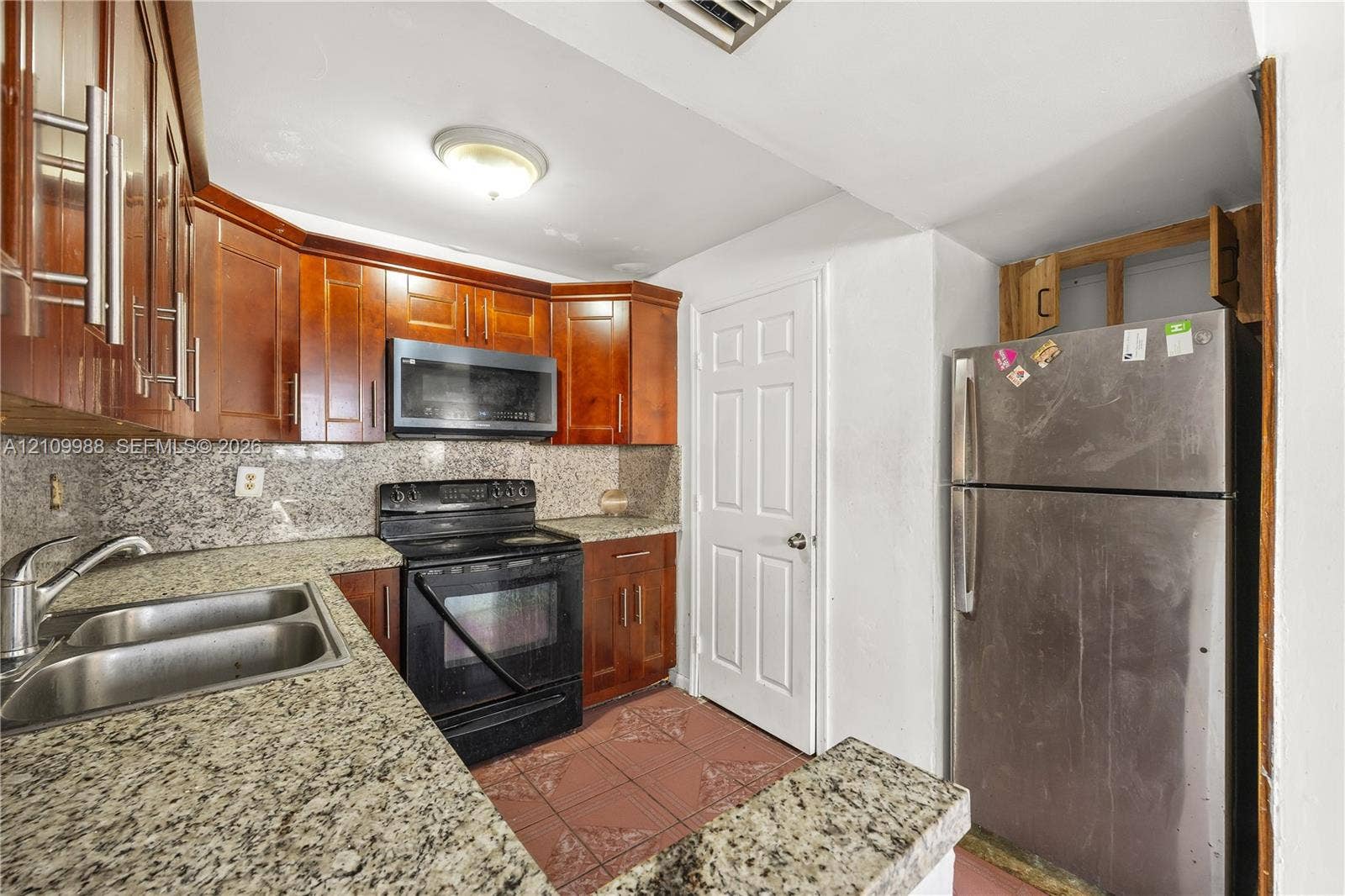 13946 NE 4th Avenue, #13946, Miami, FL 33161 Kitchen featuring wood cabinetry, stone-surface countertops, dual-basin stainless steel sink, tile flooring, and stainless steel appliances