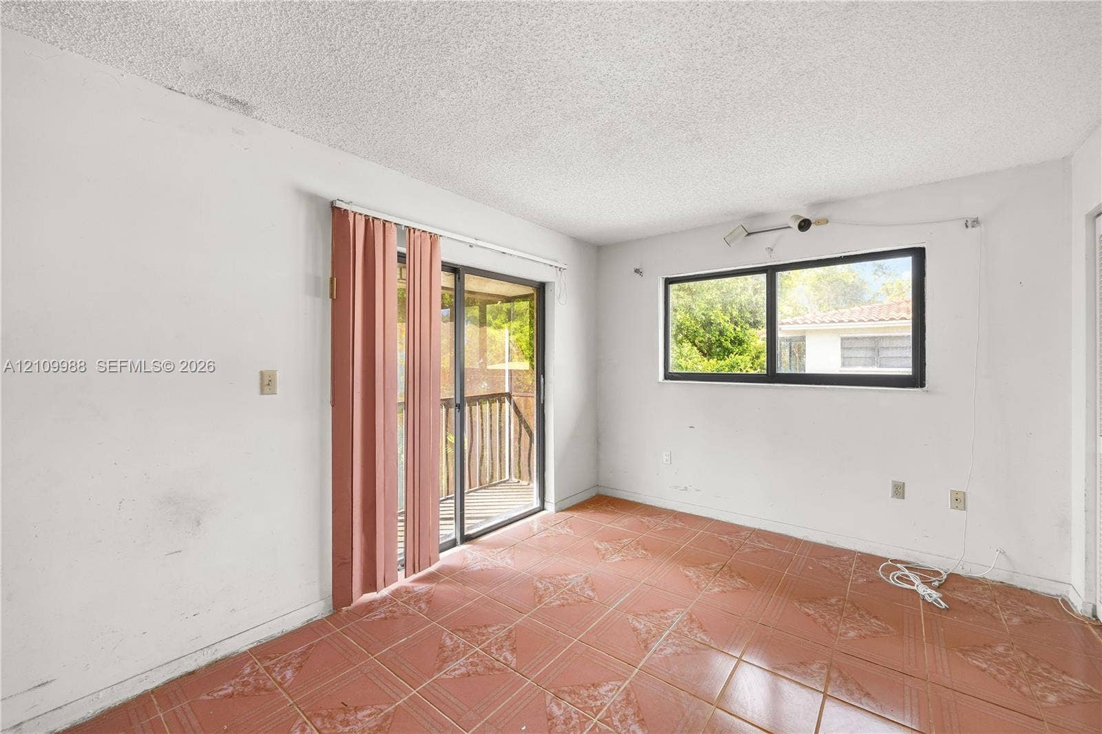 13946 NE 4th Avenue, #13946, Miami, FL 33161 Interior room featuring large-format terra cotta tile flooring, sliding glass door with external screen, and horizontal windows with black frames
