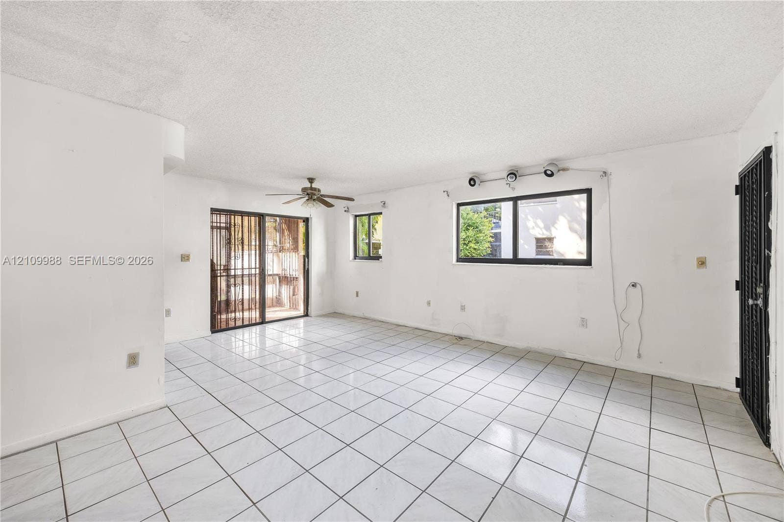 13946 NE 4th Avenue, #13946, Miami, FL 33161 Interior space featuring large-format ceramic tile flooring, a multi-blade ceiling fan, metal security door, and sliding glass patio door