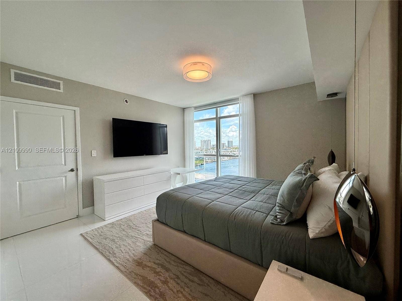 Floor-to-ceiling windows with water backdrop, polished tile flooring, flush-mount lighting, and neutral wall tones