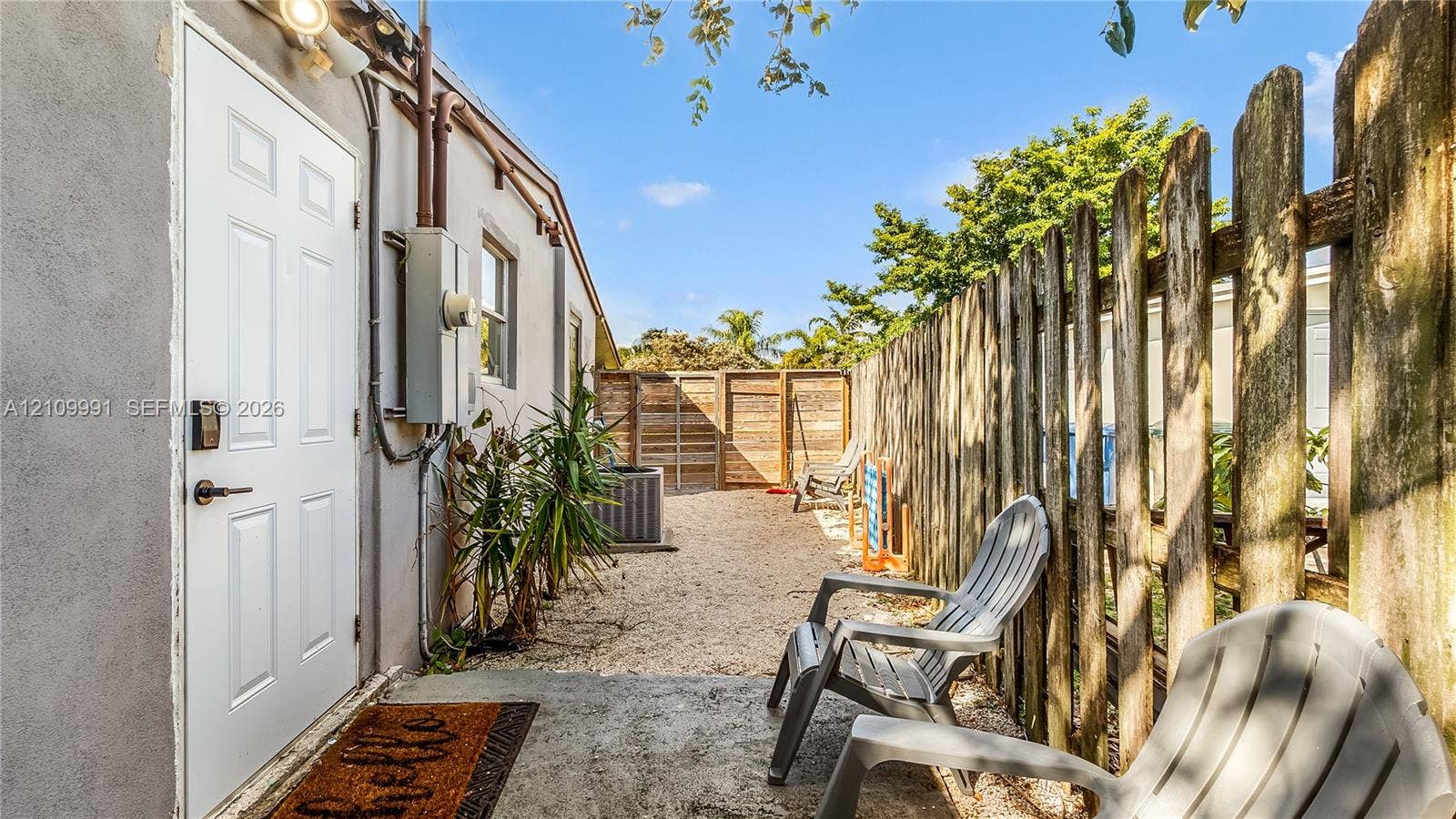Exterior space featuring a concrete patio, gravel ground cover, and enclosed wood privacy fencing