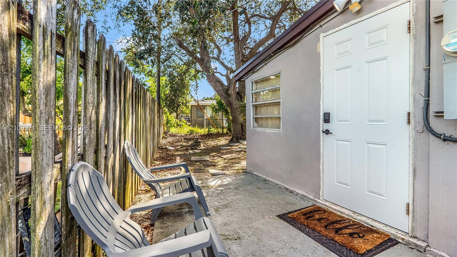 Concrete patio featuring a vertical-panel wood fence, exterior door with a smart lock, and horizontal sliding window