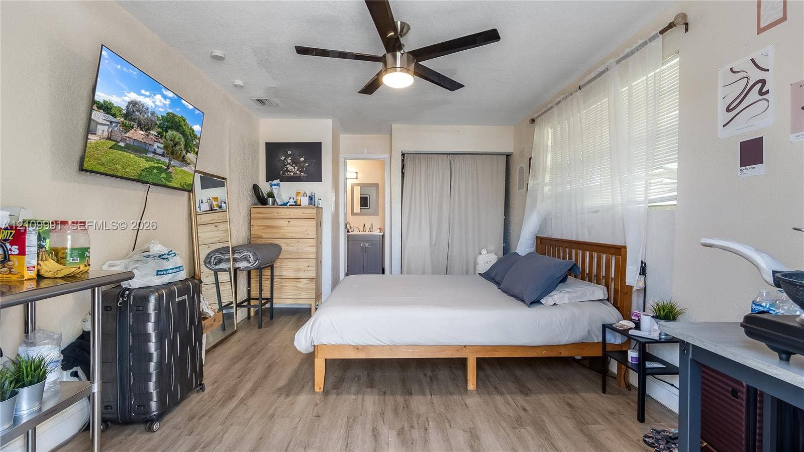 Neutral-toned room featuring wood-finish flooring, a ceiling fan with integrated lighting, and a closet with sliding doors