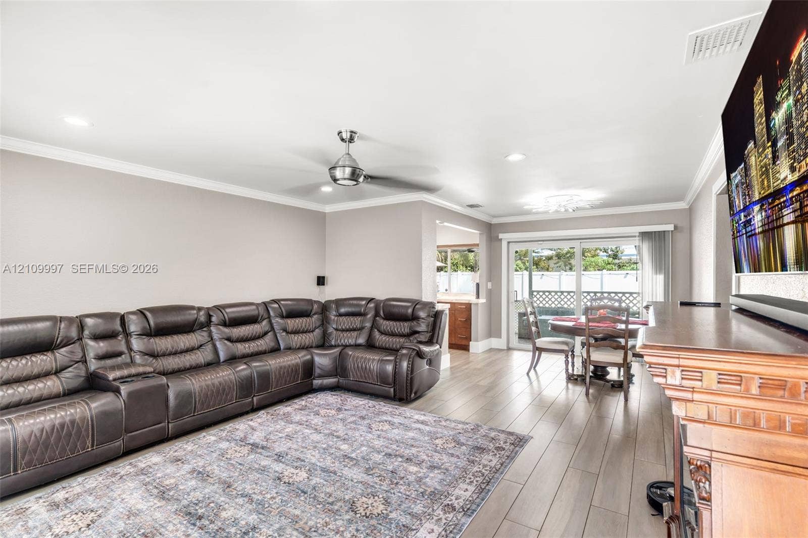 Living area featuring wood-finish flooring, crown molding, recessed lighting, a ceiling fan, and sliding glass doors