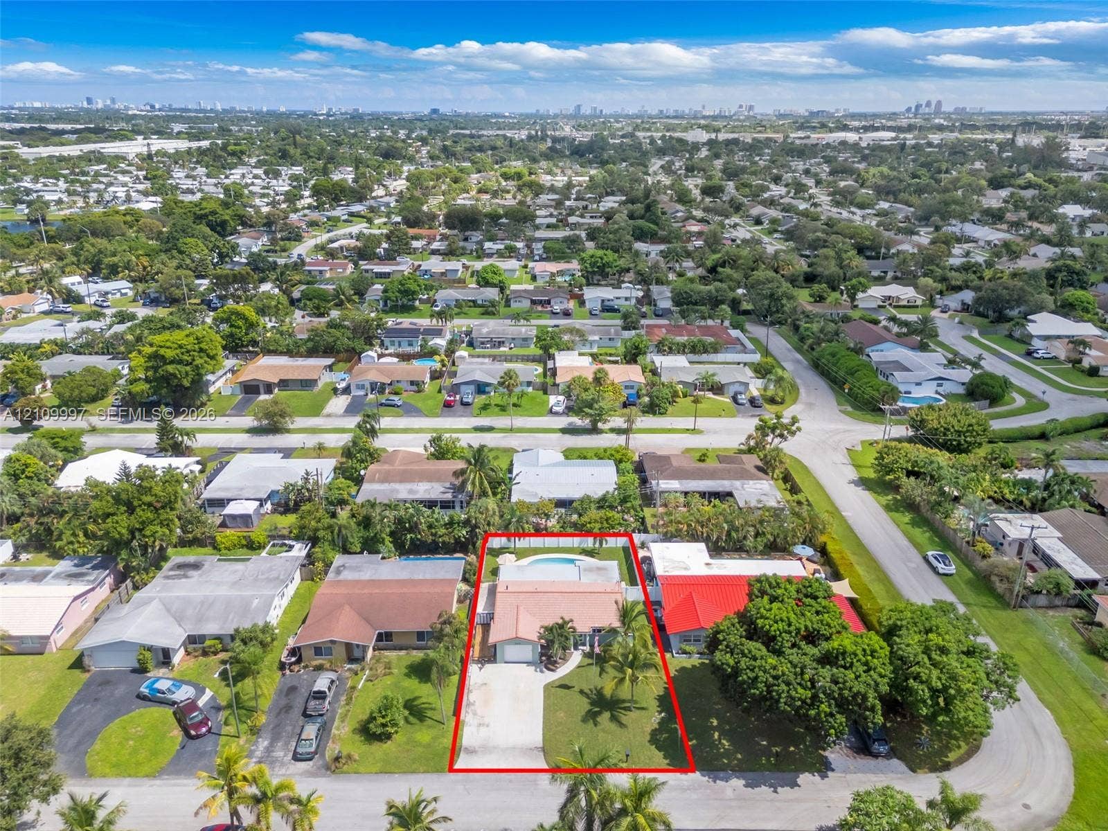 Aerial perspective featuring a concrete driveway, attached garage, tile roof, and a backyard swimming pool