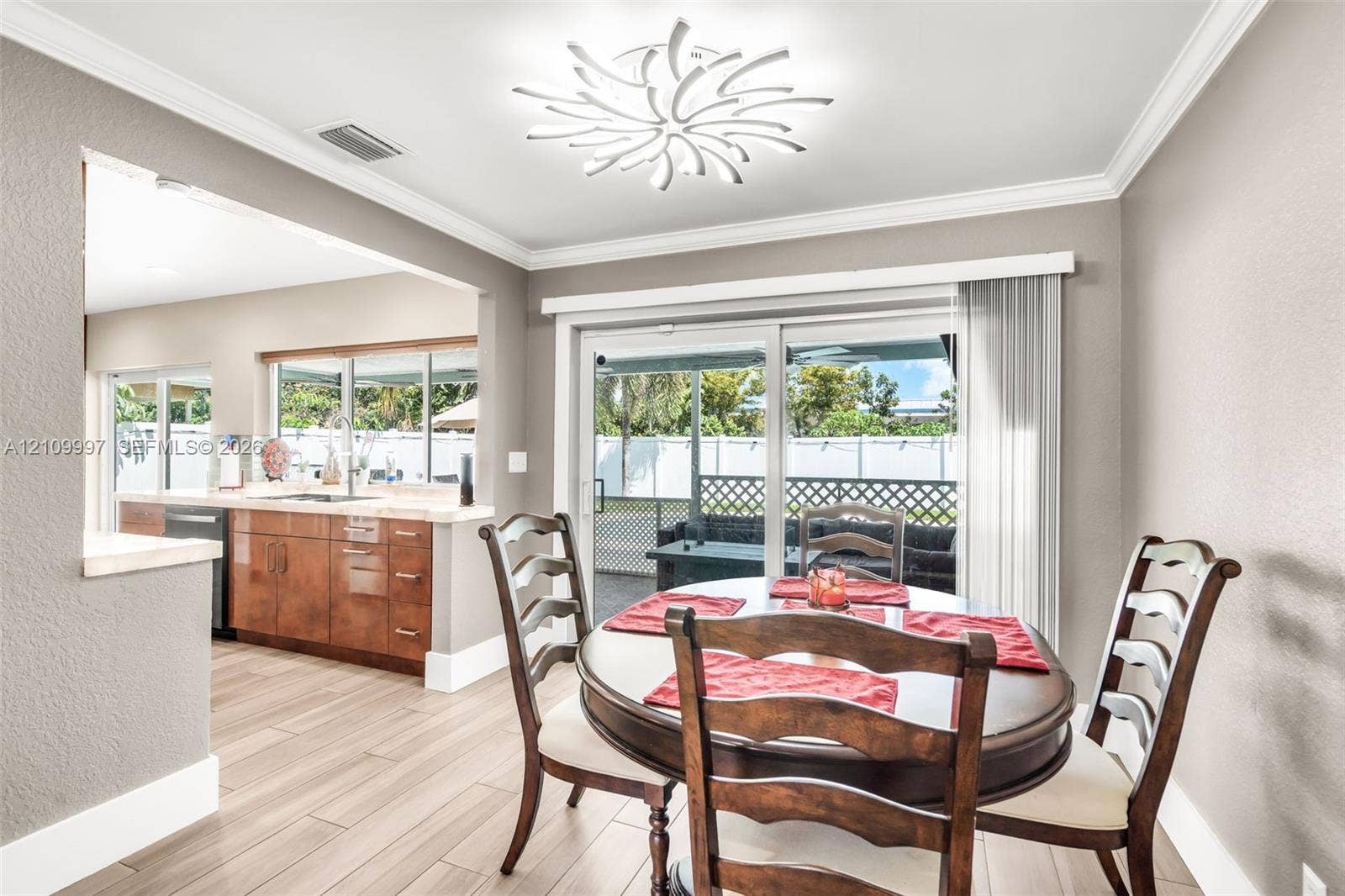 Dining area featuring wood-finish flooring, a decorative contemporary ceiling light fixture, and glass sliding doors providing exterior access
