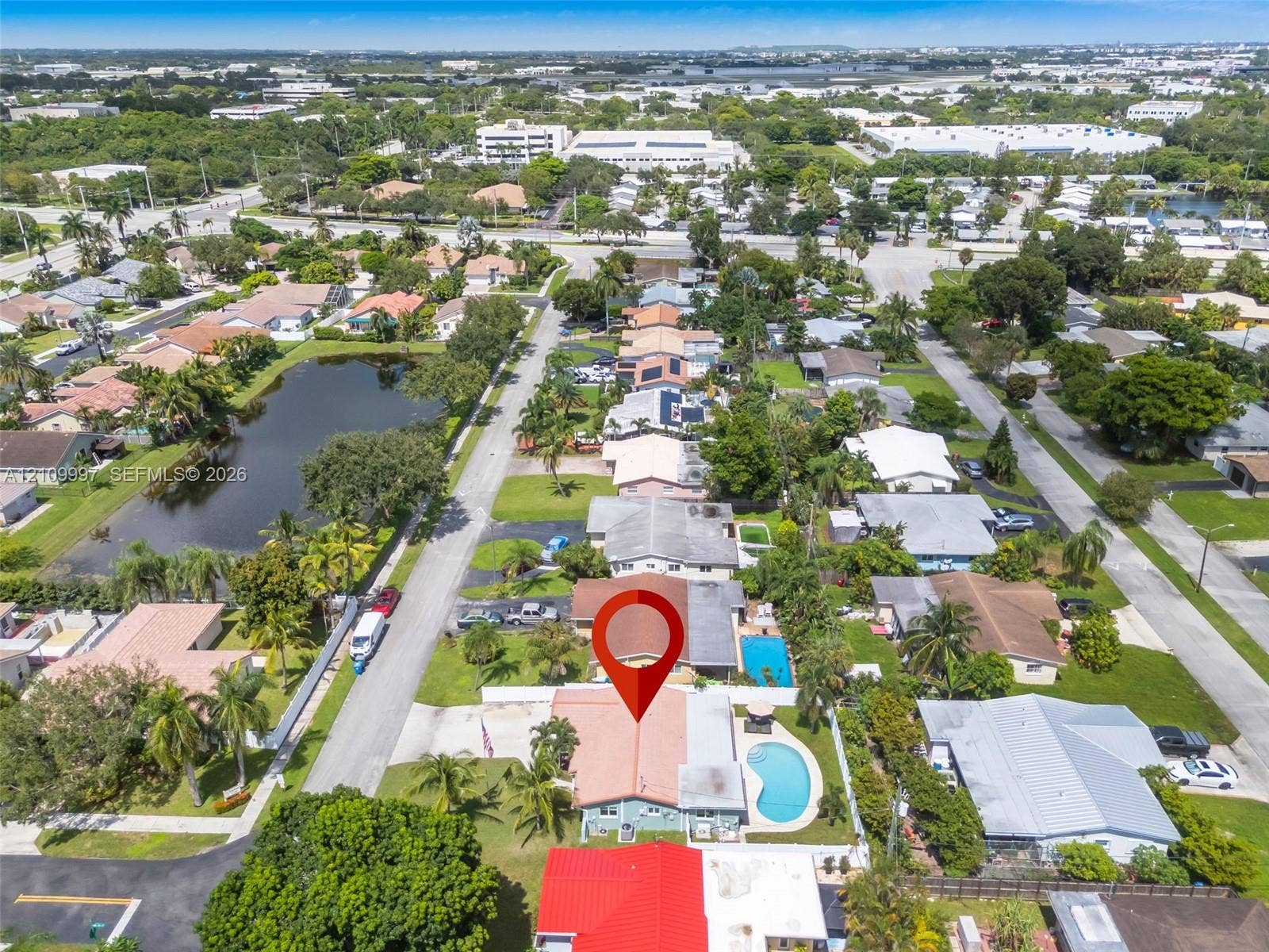Aerial perspective featuring a single-story residence with a tiled roof, private swimming pool, fenced perimeter, and mature landscaping