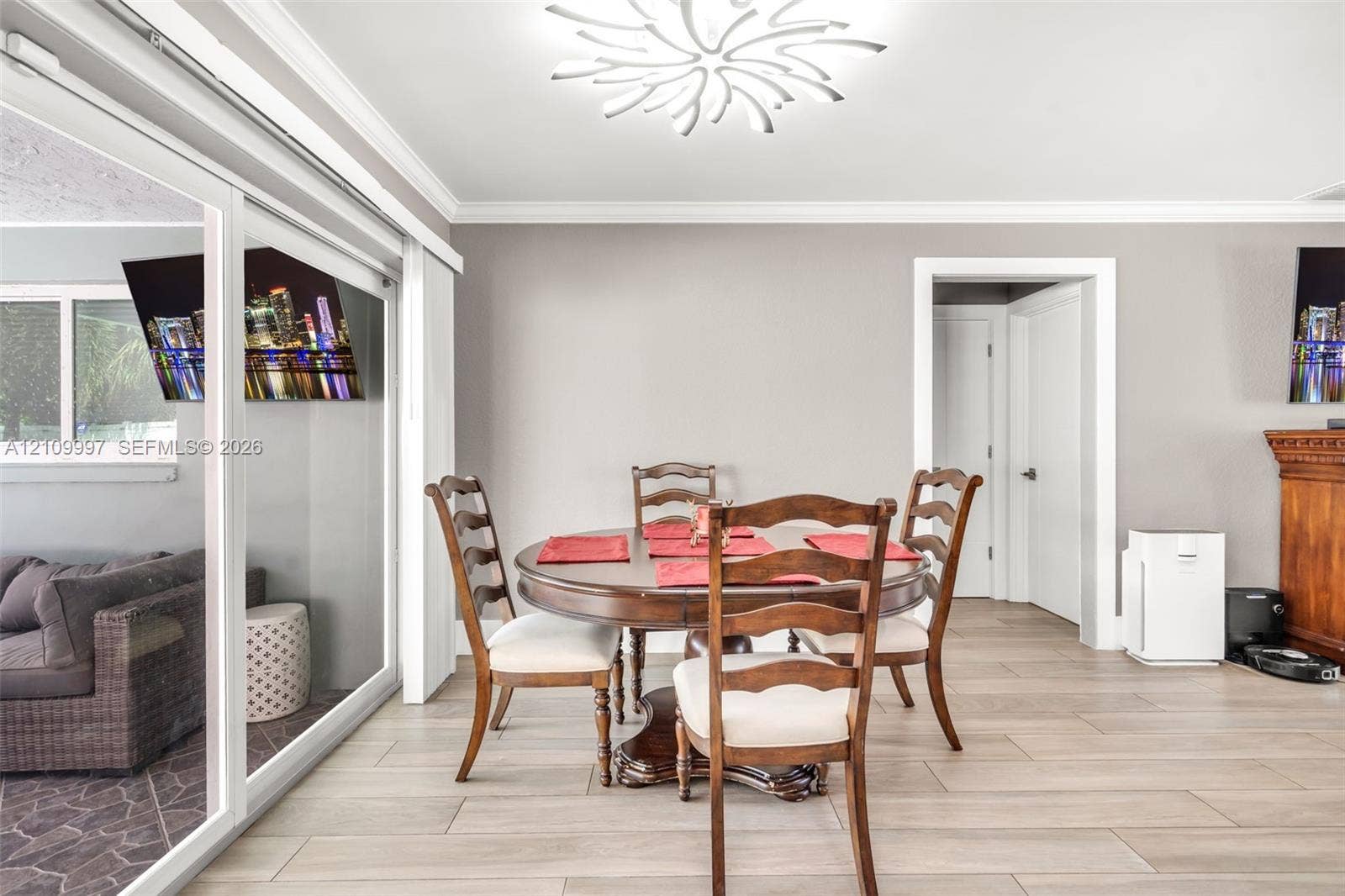 Wood-finish tile flooring, decorative sculptural ceiling lighting, crown molding, and a large sliding glass door with a white frame