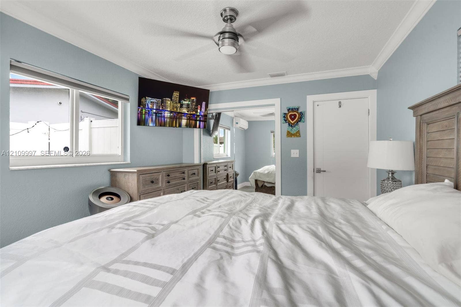 Bedroom featuring crown molding, a brushed-nickel ceiling fan, double-pane windows, and a wall-mounted climate control unit