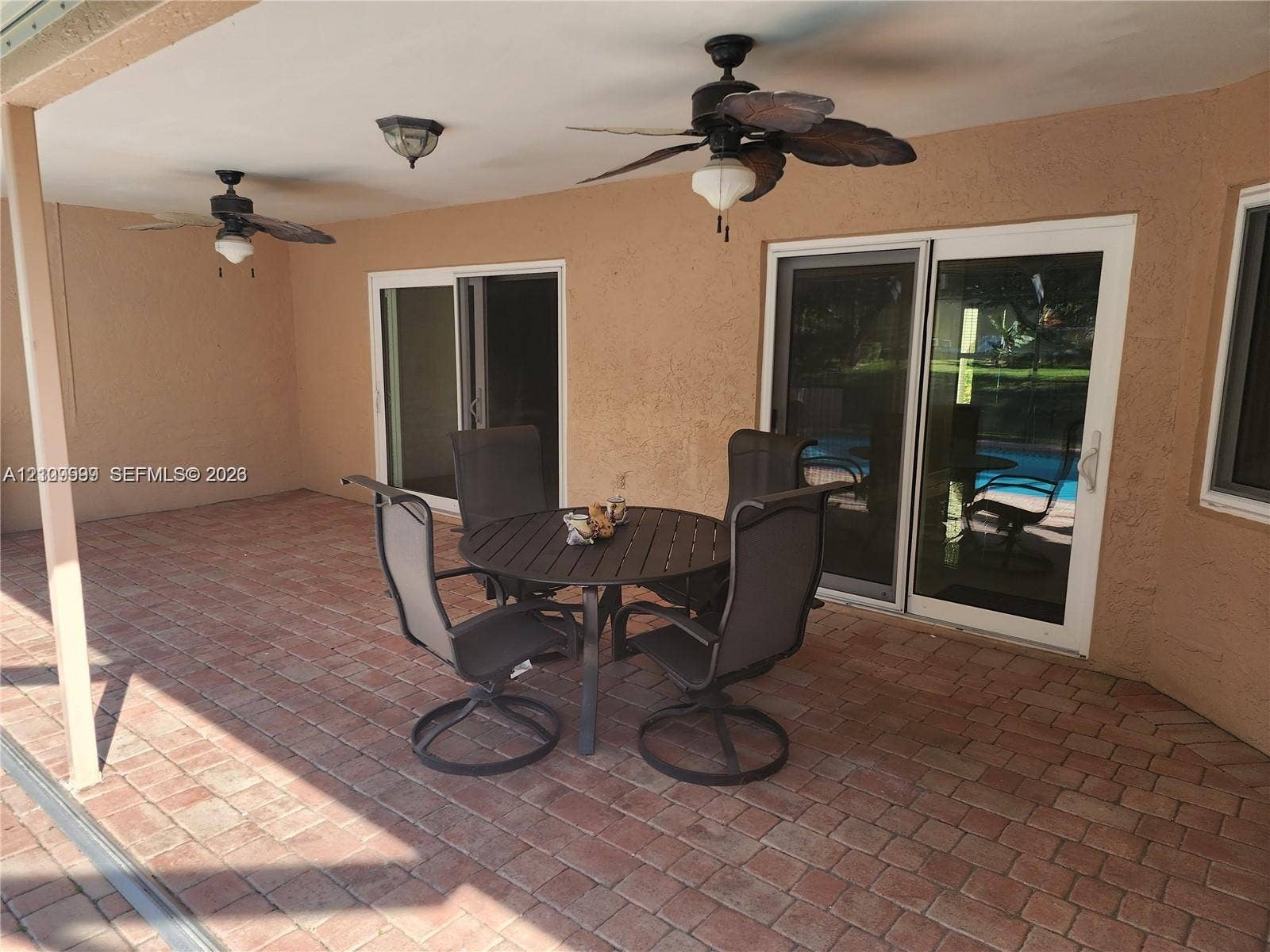 1794 NW 112th Terrace, Coral Springs, Coral Springs, FL 33071 Covered patio featuring brick pavers, dual ceiling fans with integrated lighting, and double sliding glass doors
