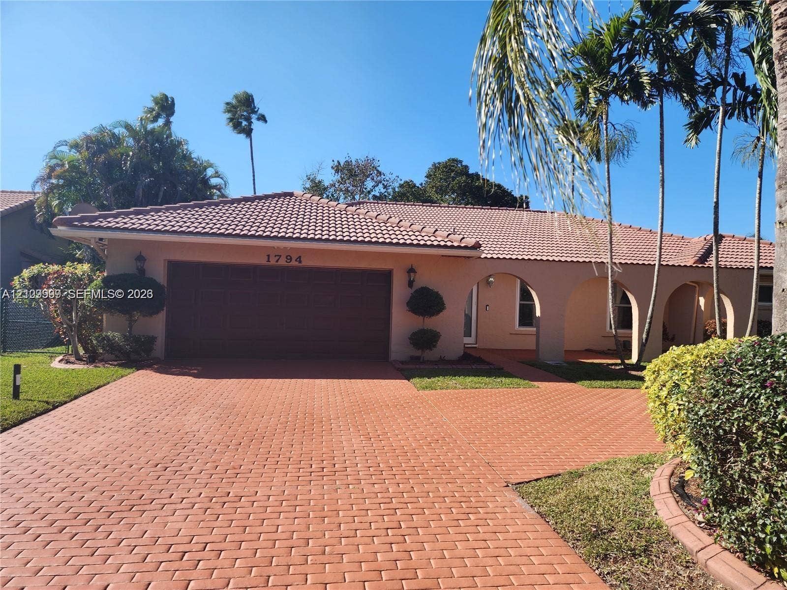 1794 NW 112th Terrace, Coral Springs, Coral Springs, FL 33071 Stucco exterior featuring a clay tile roof, arched covered entry, paver driveway, and mature landscaping