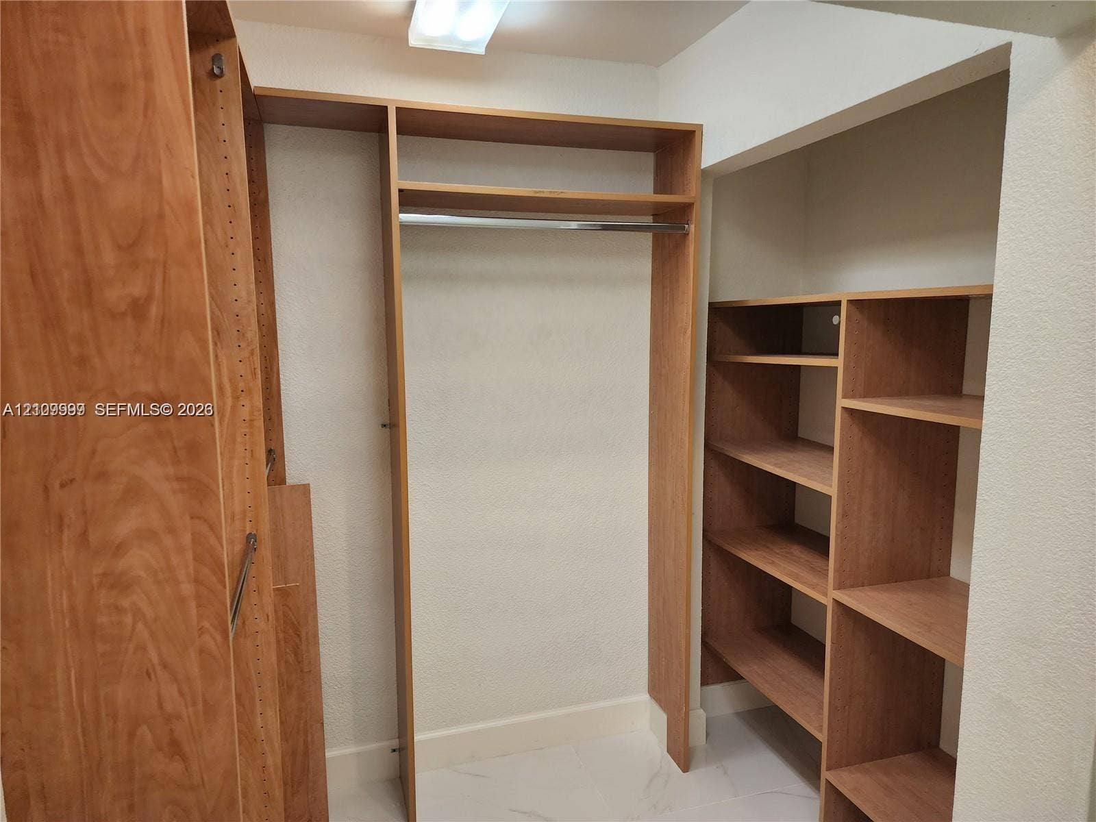 1794 NW 112th Terrace, Coral Springs, Coral Springs, FL 33071 Custom wood-finish closet system featuring vertical shelving units, horizontal storage racks, and an integrated hanging rod