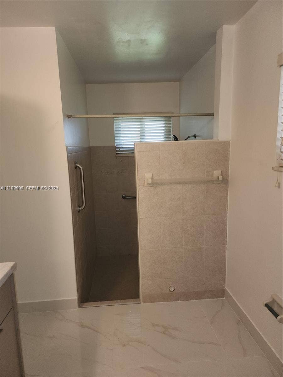1794 NW 112th Terrace, Coral Springs, Coral Springs, FL 33071 Walk-in shower featuring neutral tile surround, metal grab bars, built-in recessed shelf, and light-toned tile flooring