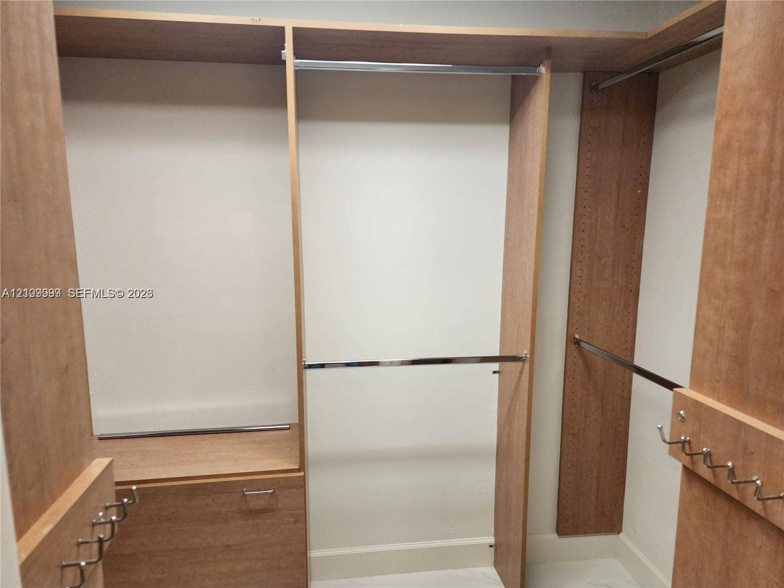 1794 NW 112th Terrace, Coral Springs, Coral Springs, FL 33071 Custom wood-finish shelving unit featuring tiered hanging rods, built-in cabinetry, and integrated metal hooks