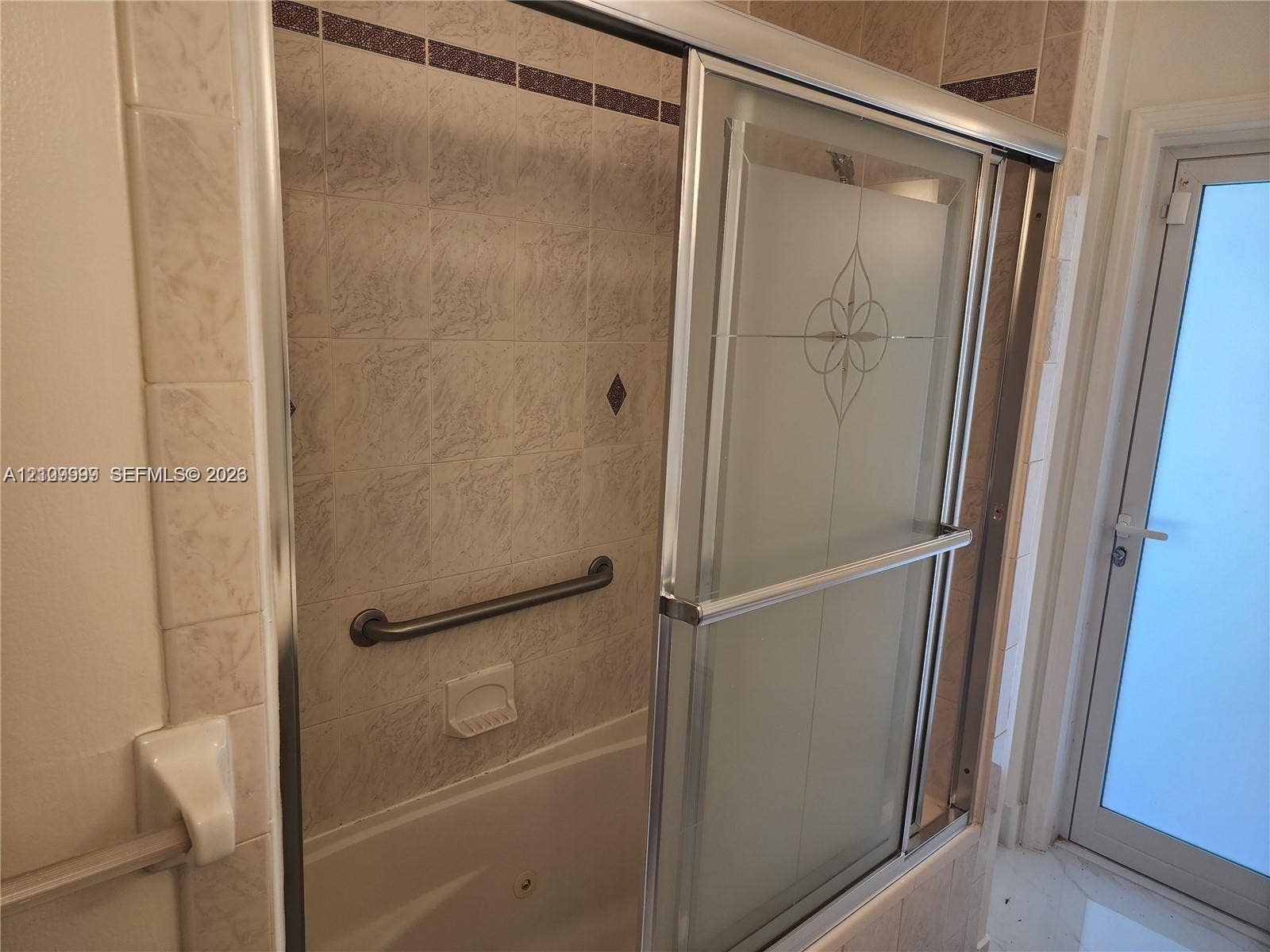 1794 NW 112th Terrace, Coral Springs, Coral Springs, FL 33071 Tub and shower combination featuring a glass enclosure with decorative etching, integrated wall-mounted grab bar, built-in soap dish, and neutral ceramic tile surround with accent detailing