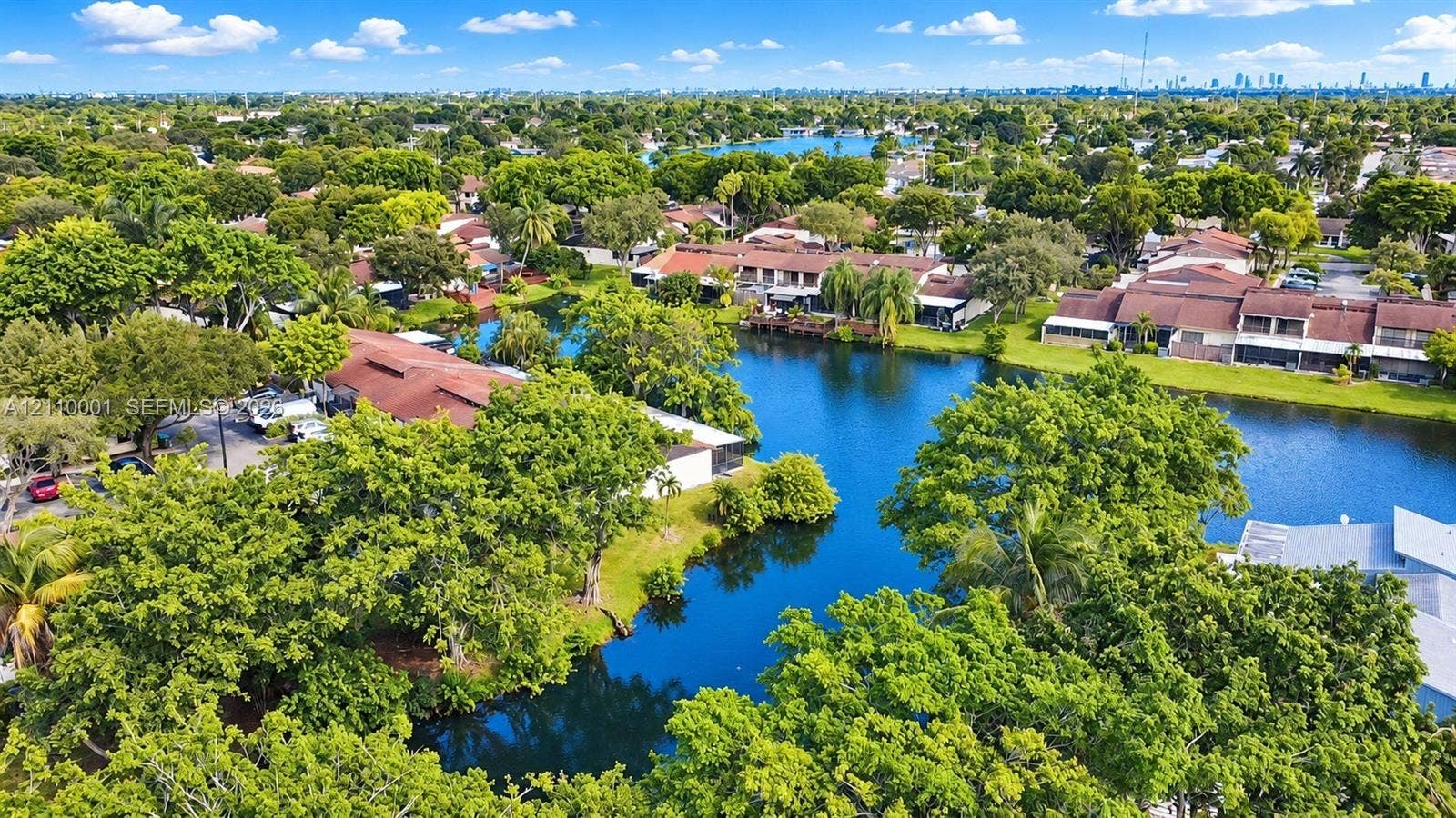 3617 SW 69th Terrace, #24-Z, Miramar, FL 33023 Aerial perspective featuring waterfront property, multi-unit residential structures, red-tiled rooflines, and mature canopy trees