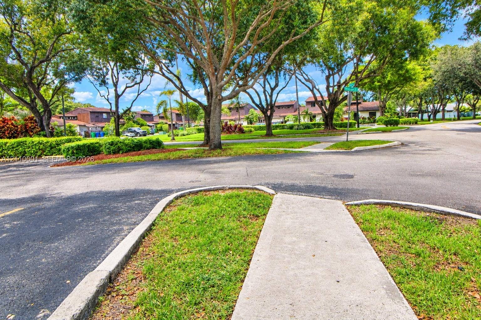 3617 SW 69th Terrace, #24-Z, Miramar, FL 33023 Asphalt street infrastructure featuring concrete curbing and paved pedestrian sidewalks shaded by mature canopy trees
