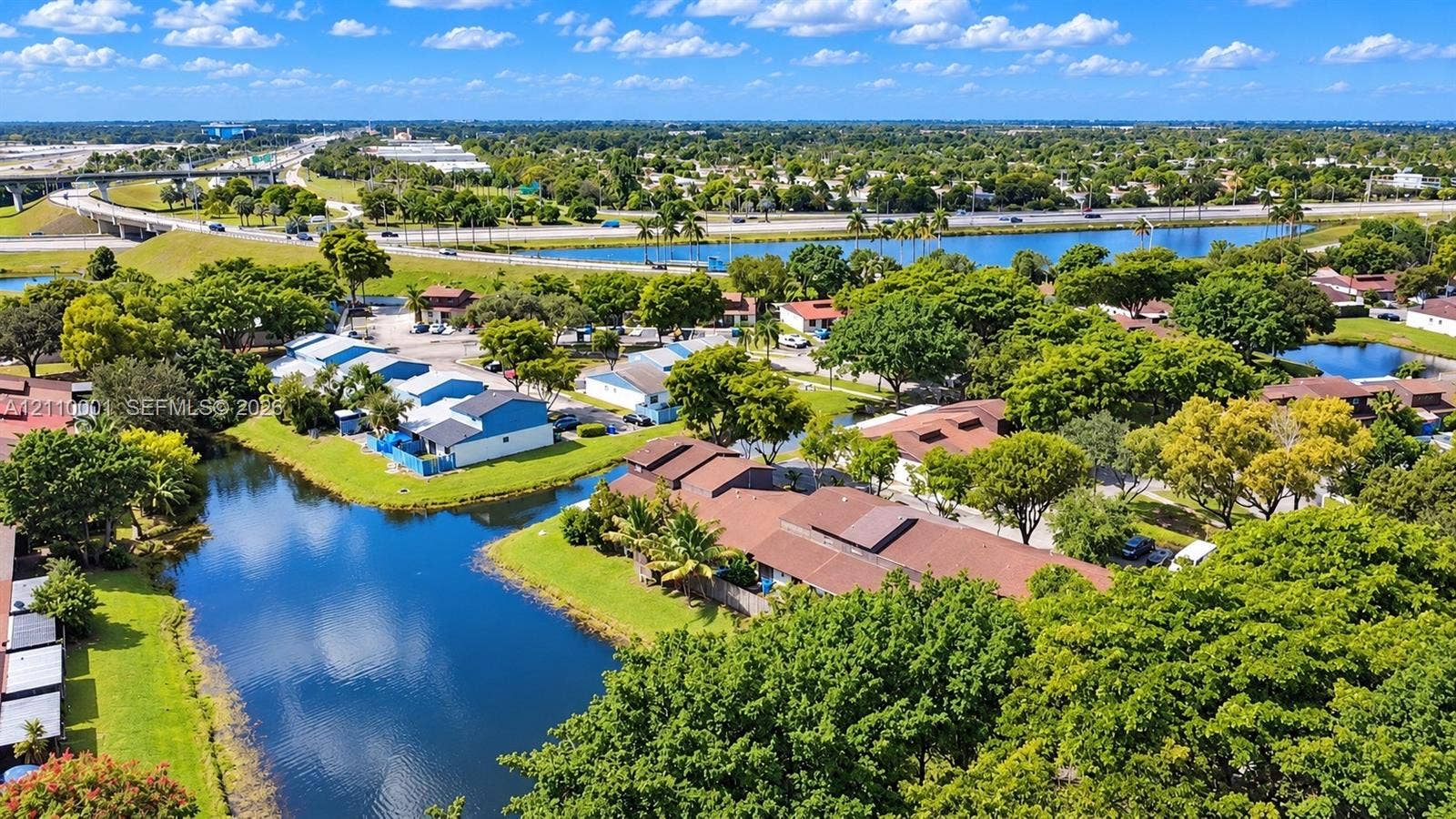 3617 SW 69th Terrace, #24-Z, Miramar, FL 33023 Aerial perspective of a multi-unit residential property featuring waterfront positioning, expansive green space, mature landscaping, and brown shingle roofing