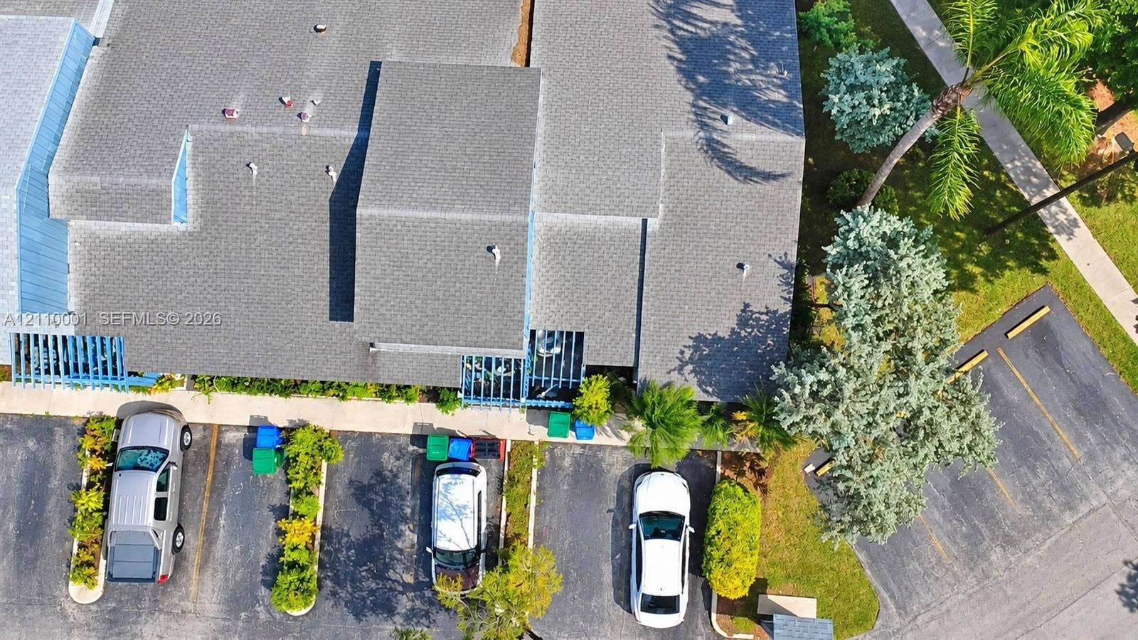 3617 SW 69th Terrace, #24-Z, Miramar, FL 33023 Aerial perspective of property featuring shingled roof lines, blue structural lattice accents, paved parking area, and mature landscape elements