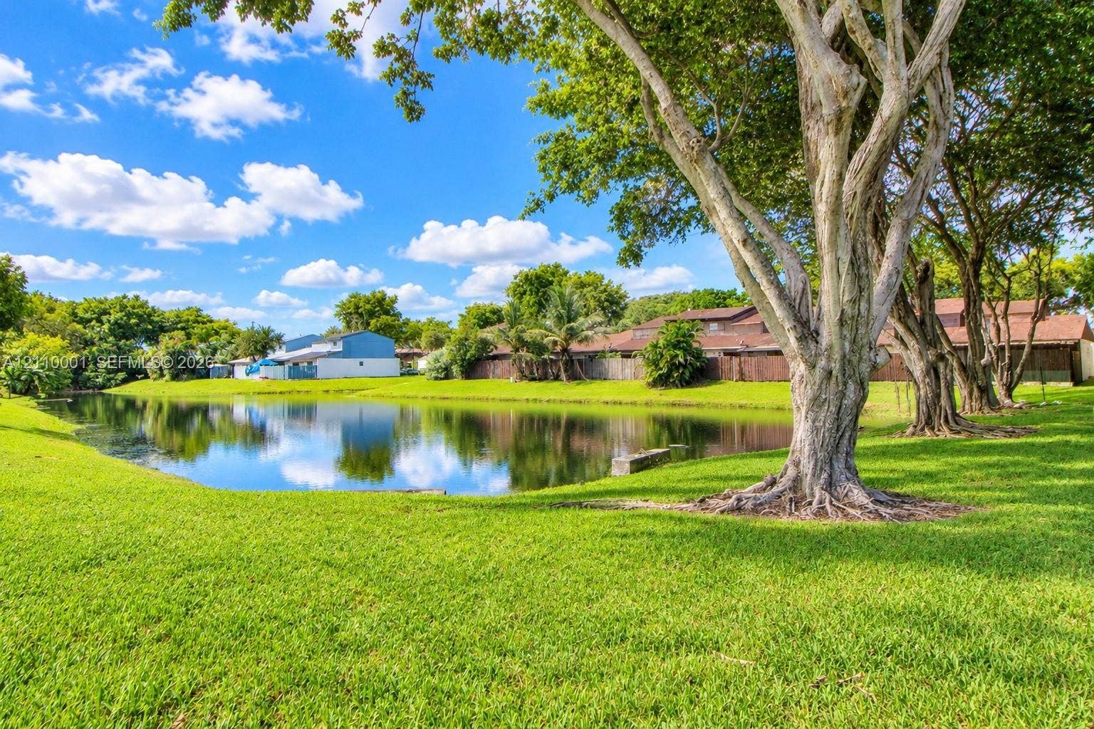 3617 SW 69th Terrace, #24-Z, Miramar, FL 33023 Waterfront lot featuring a manicured lawn, mature shade trees, and perimeter privacy fencing
